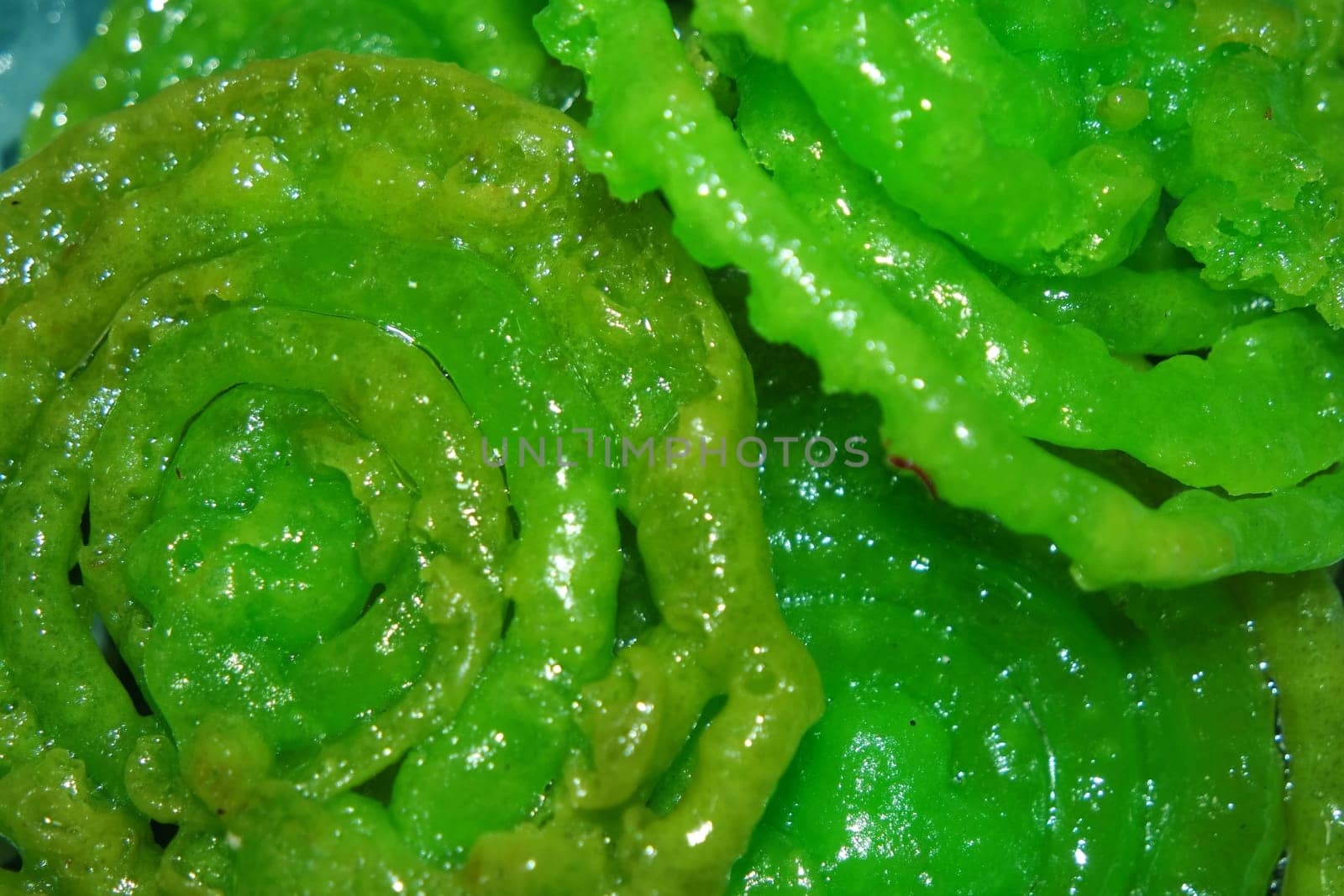 Crispy sweet Asian dessert green Jalebi cooked and served in Festival, Indian sweet street food with juicy syrup, a closeup view.