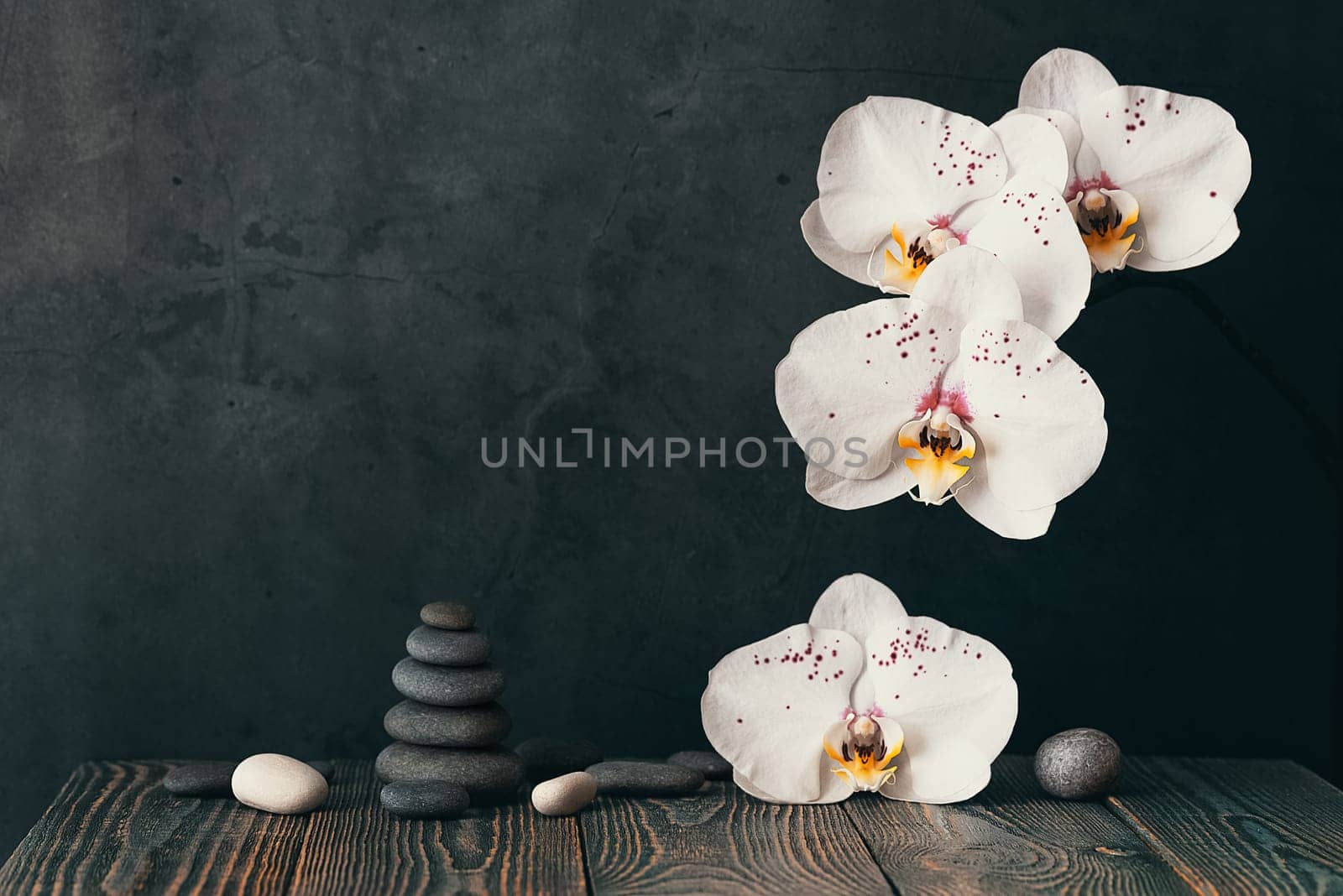 tower of stones and orchid flowers on a gray background
