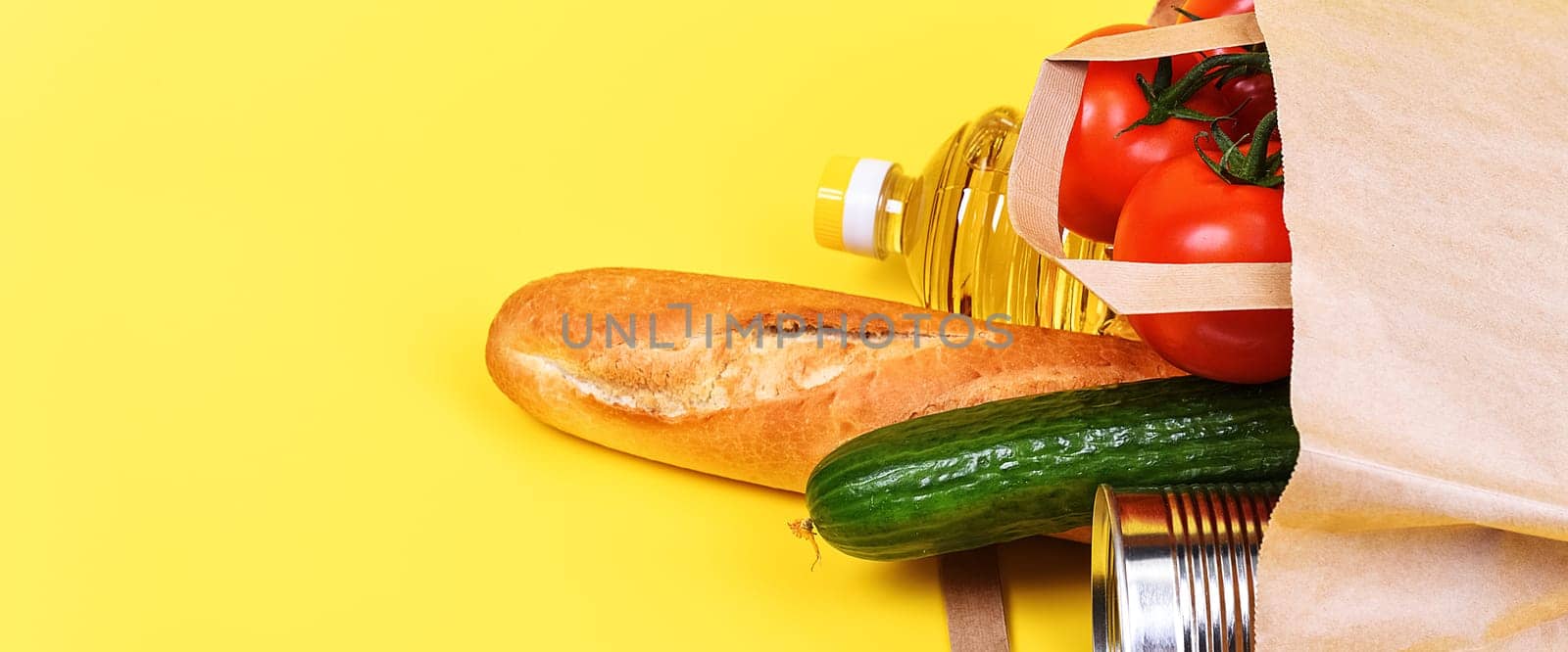Paper bag with food supplies for the period of quarantine isolation on a yellow background. Delivery, donation, coronavirus, copyspace.