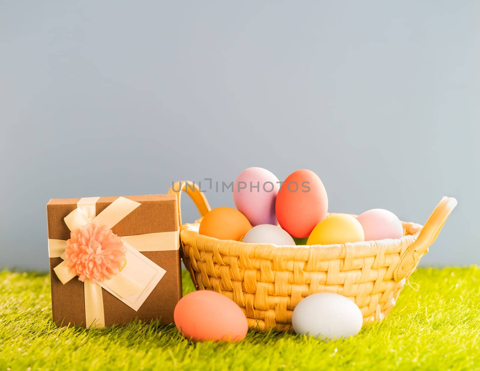 Colorful easter eggs in the basket on green grass background with copy space