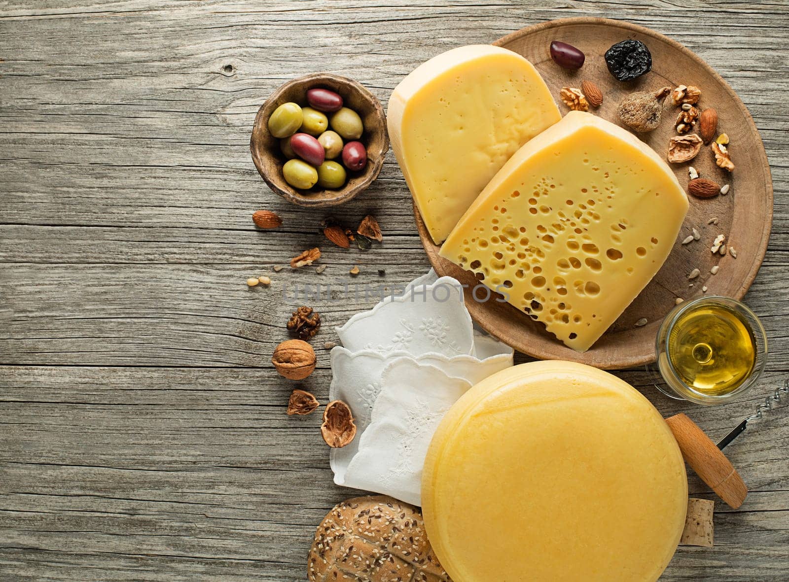 Assortment of cheese, nuts and wine on wooden table. Top view. Free space for text.