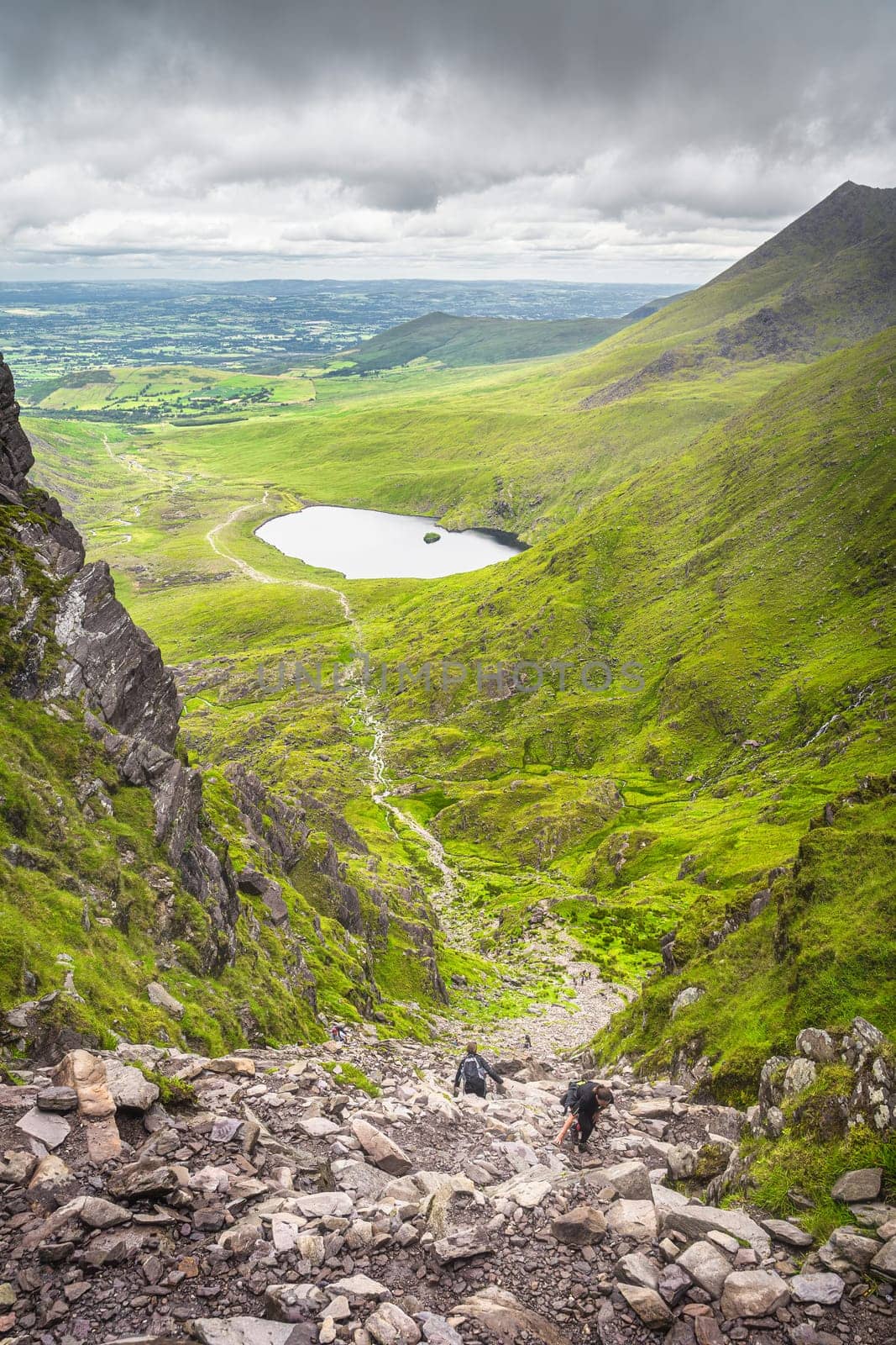 Group of hikers climbing Devils Ladder, one of most difficult trails, to reach highest Irish mountain Carrauntoohil in Ring of Kerry, Ireland