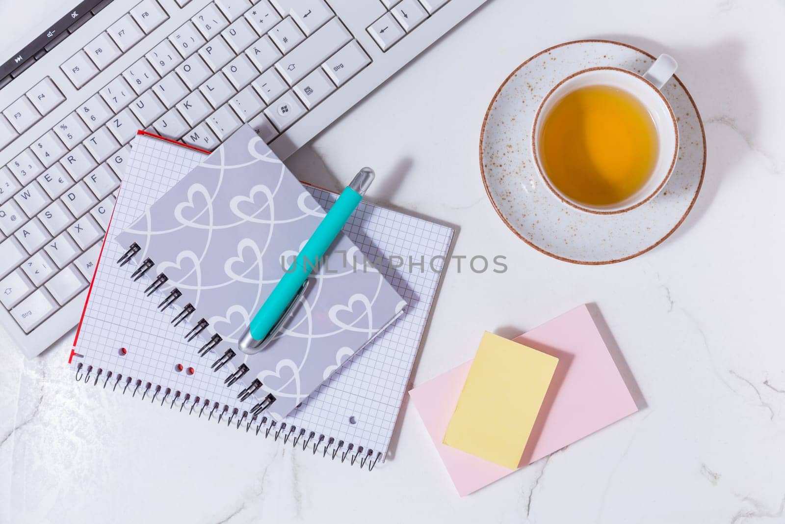 Flat lay home business desk with communication device with cup of tea and writing tools. Feminine business mockup, copyspace, white background.