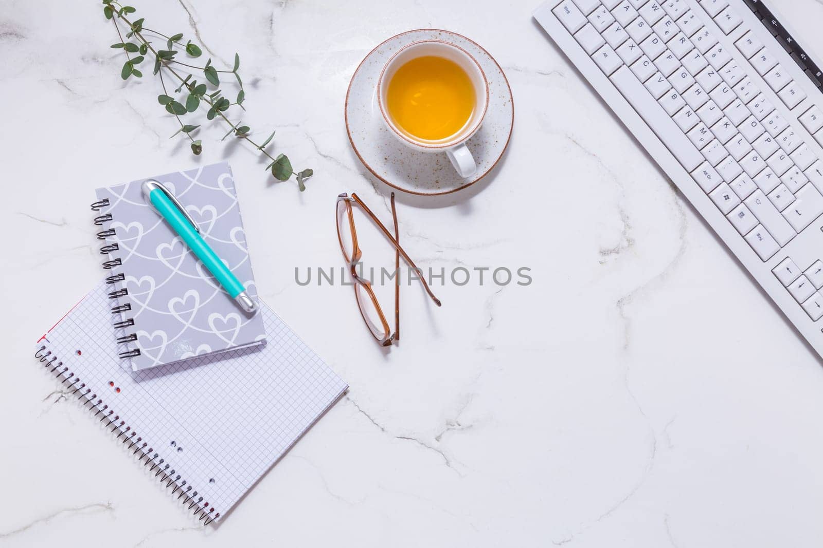 Flat lay home business desk with communication device with cup of tea and writing tools. Feminine business mockup, copyspace, white background.