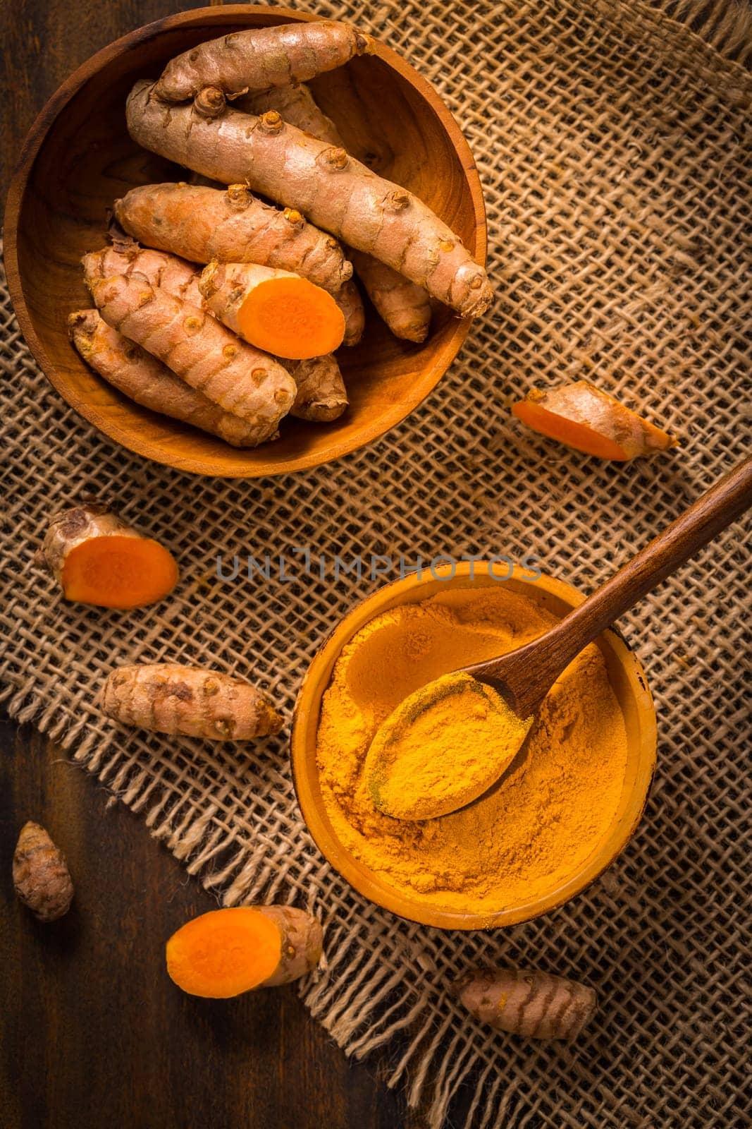 Turmeric root and powder (Curcuma longa) as cooking ingredient on wooden background