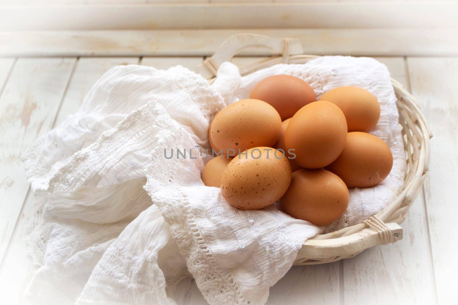 brown eggs in a wicker basket on a light wooden table in rustic style