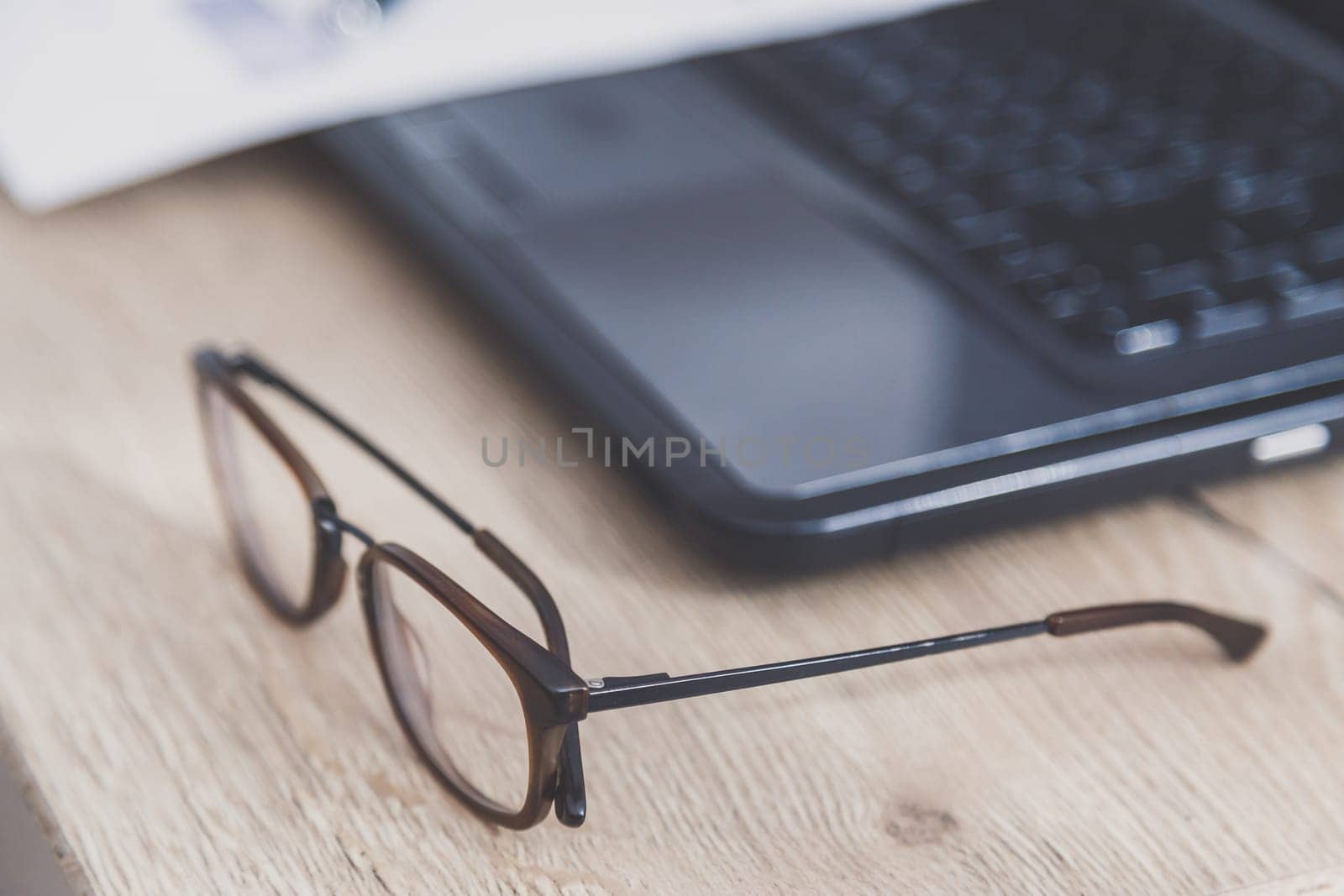 Home office desk workspace. Close-up view on eyeglasses on wooden table.