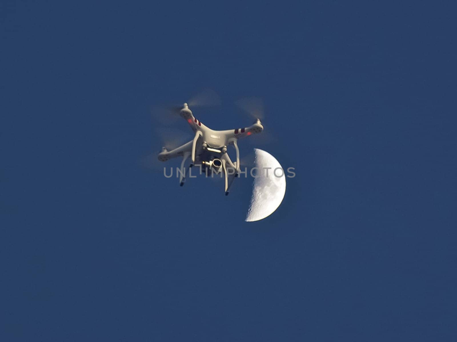 Drone against the moon and blue sky. Flying drone with camera.