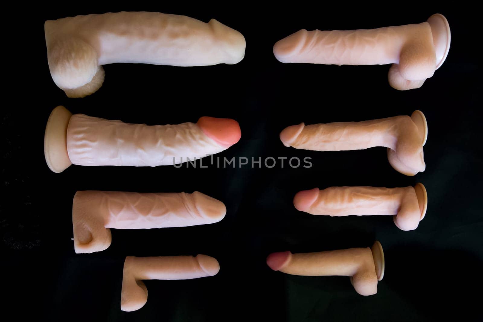 Rubber male genitalia on a black background. Sexual penis from the rubber. Rubber sexual organs.