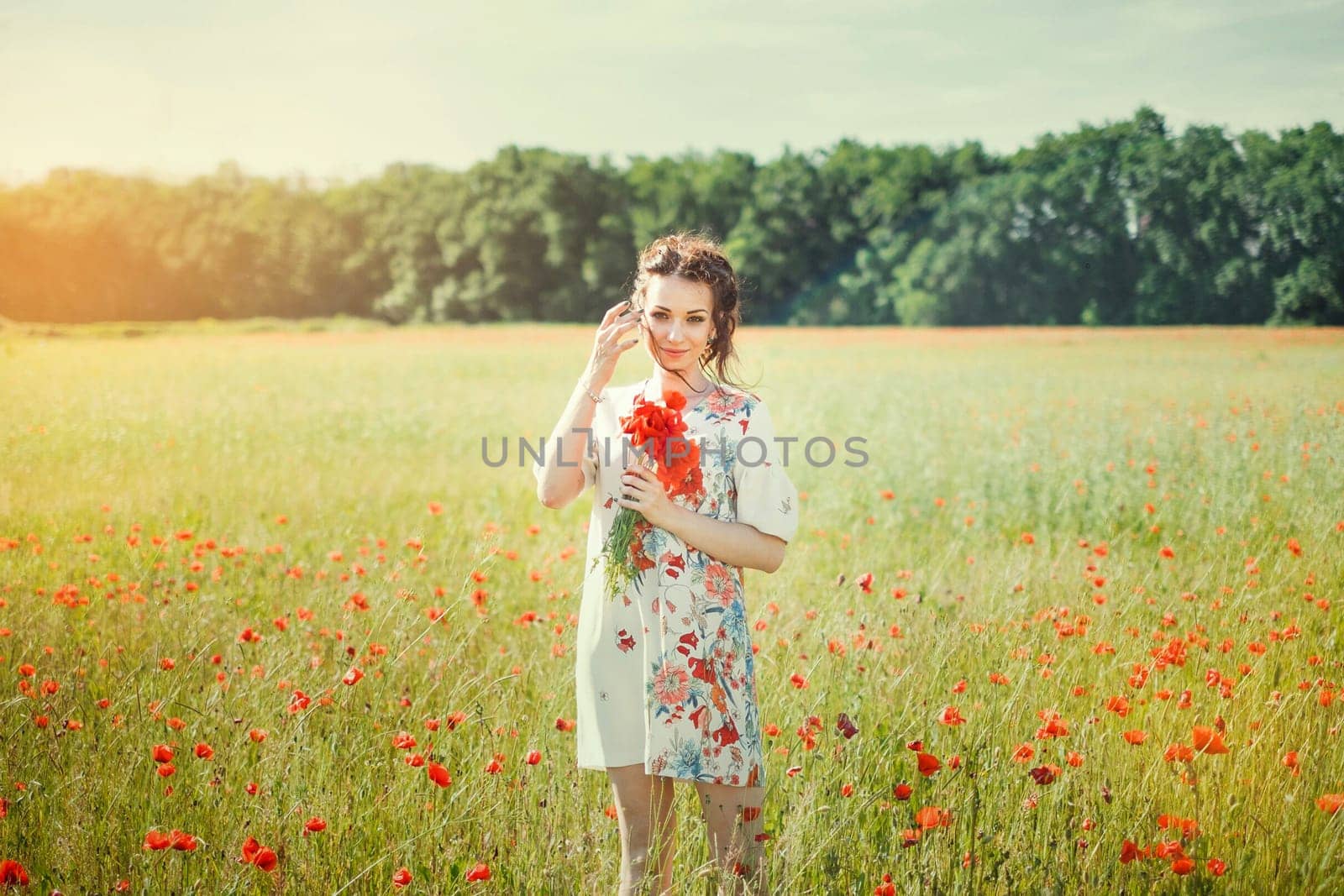 A beautiful girl in a field of blooming red poppies.