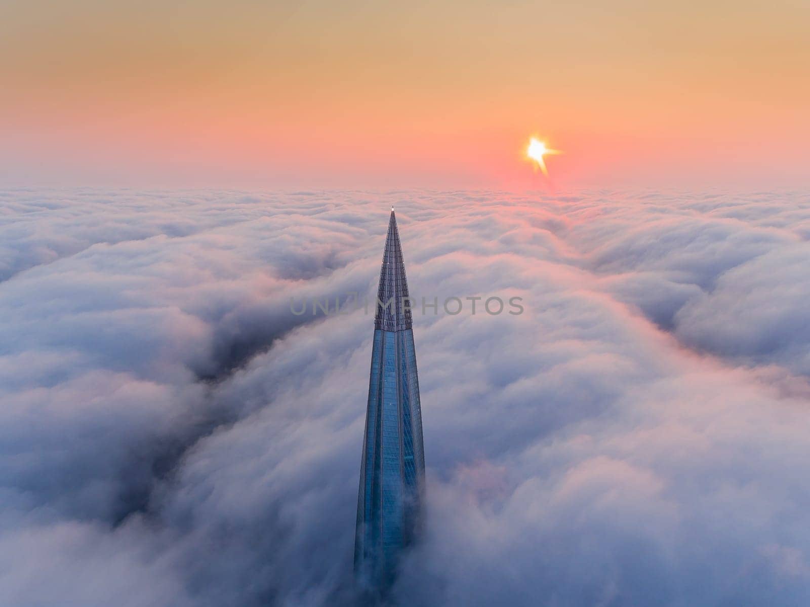 The top of the skyscraper above the fog. Fog over the city.