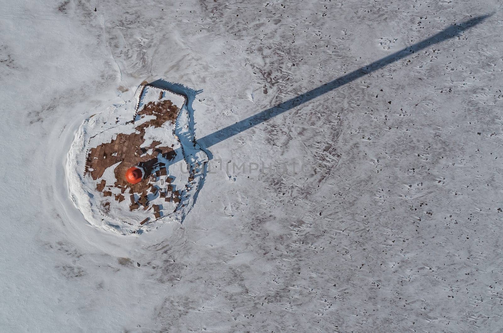 The lighthouse is in winter on the river bank. View from above.