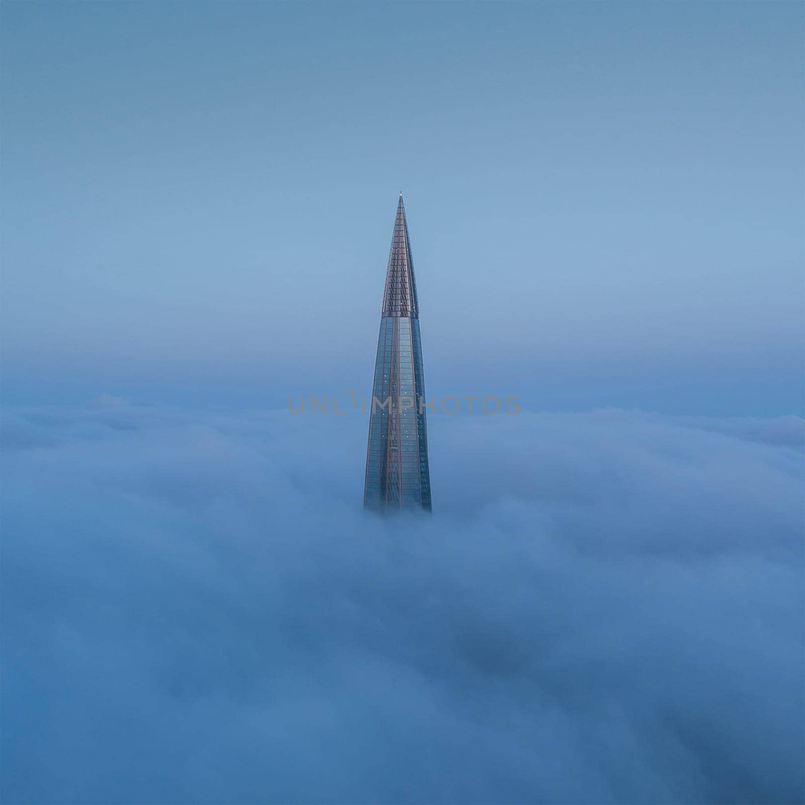 The top of the skyscraper above the fog. Fog over the city.