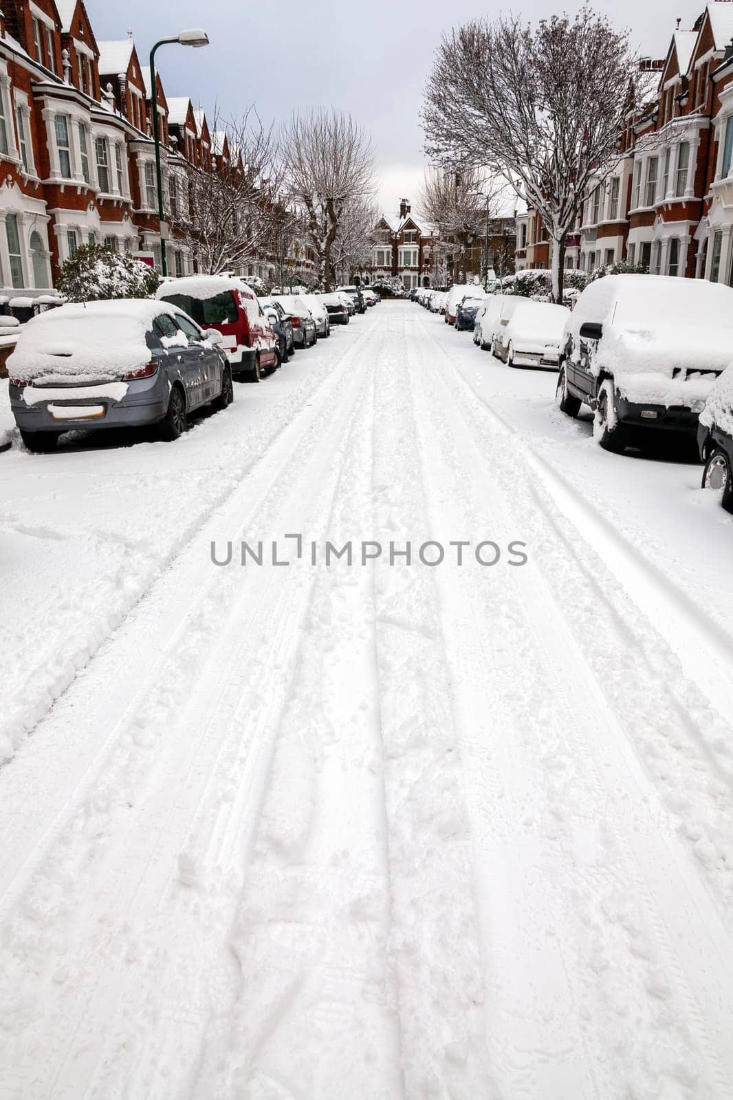 Street winter cityscape with snow terraced houses and frozen cars after a blizzard snowfall in London England UK, stock photo image with copy space