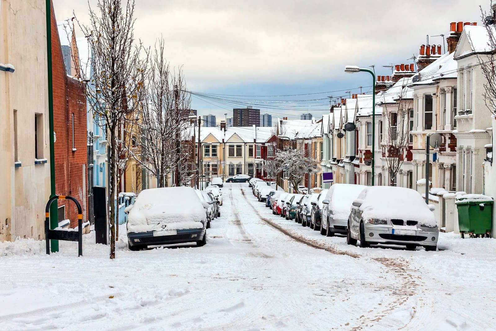 Street winter cityscape with snow terraced houses and frozen cars after a blizzard snowfall in London England UK, stock photo image with copy space