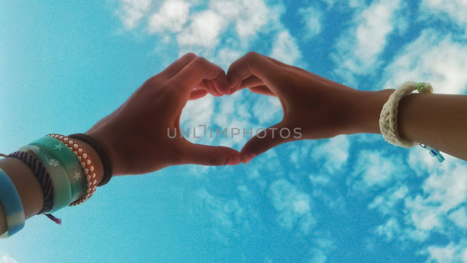 Hands in the sky and heart symbol fingers show.