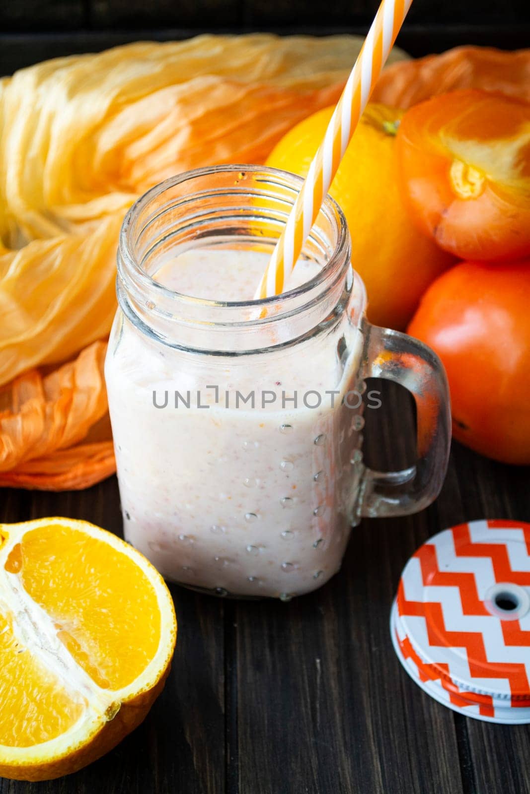Healthy persimmon and orange smoothie in glass jars, vertical image
