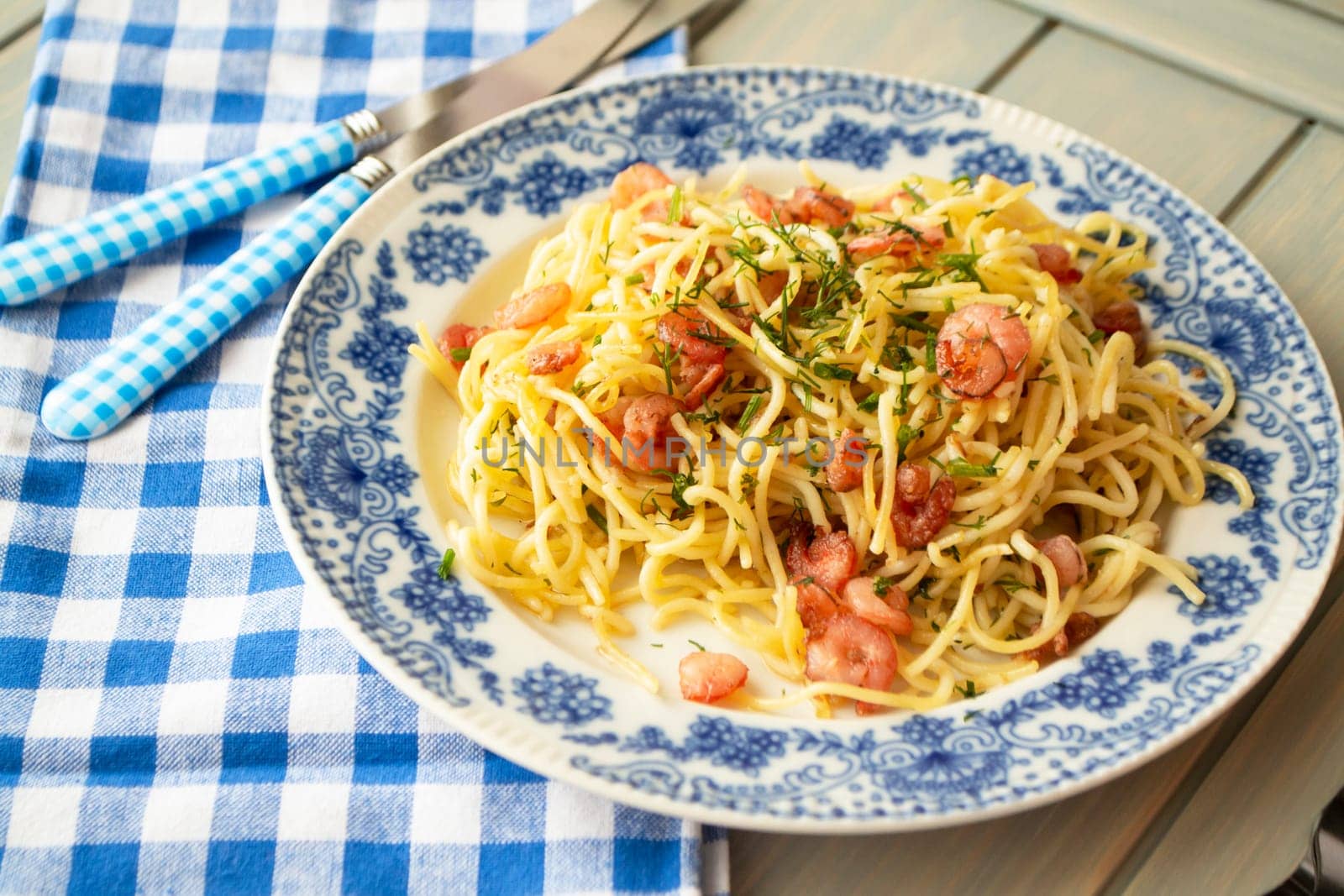 Spaghetti with shrimps and chopped parsley on plate with blue decoration