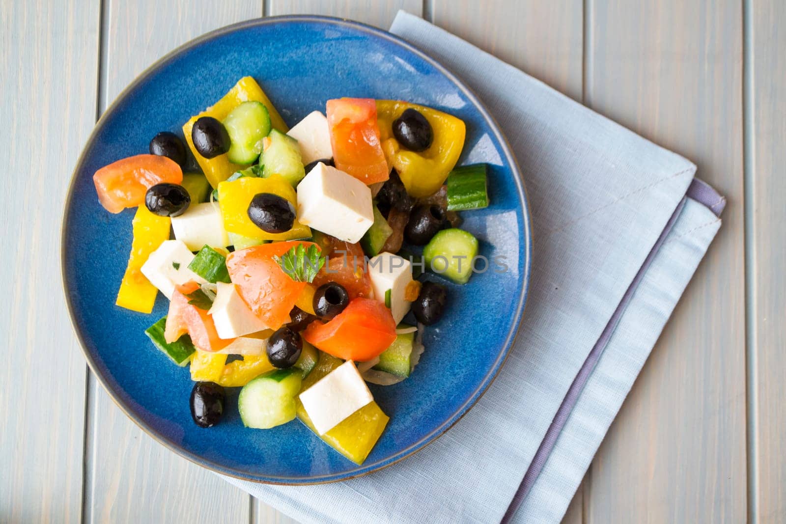 Greek salad of organic vegetables with tomatoes, cucumber, red onion, olives and feta cheese. Top view