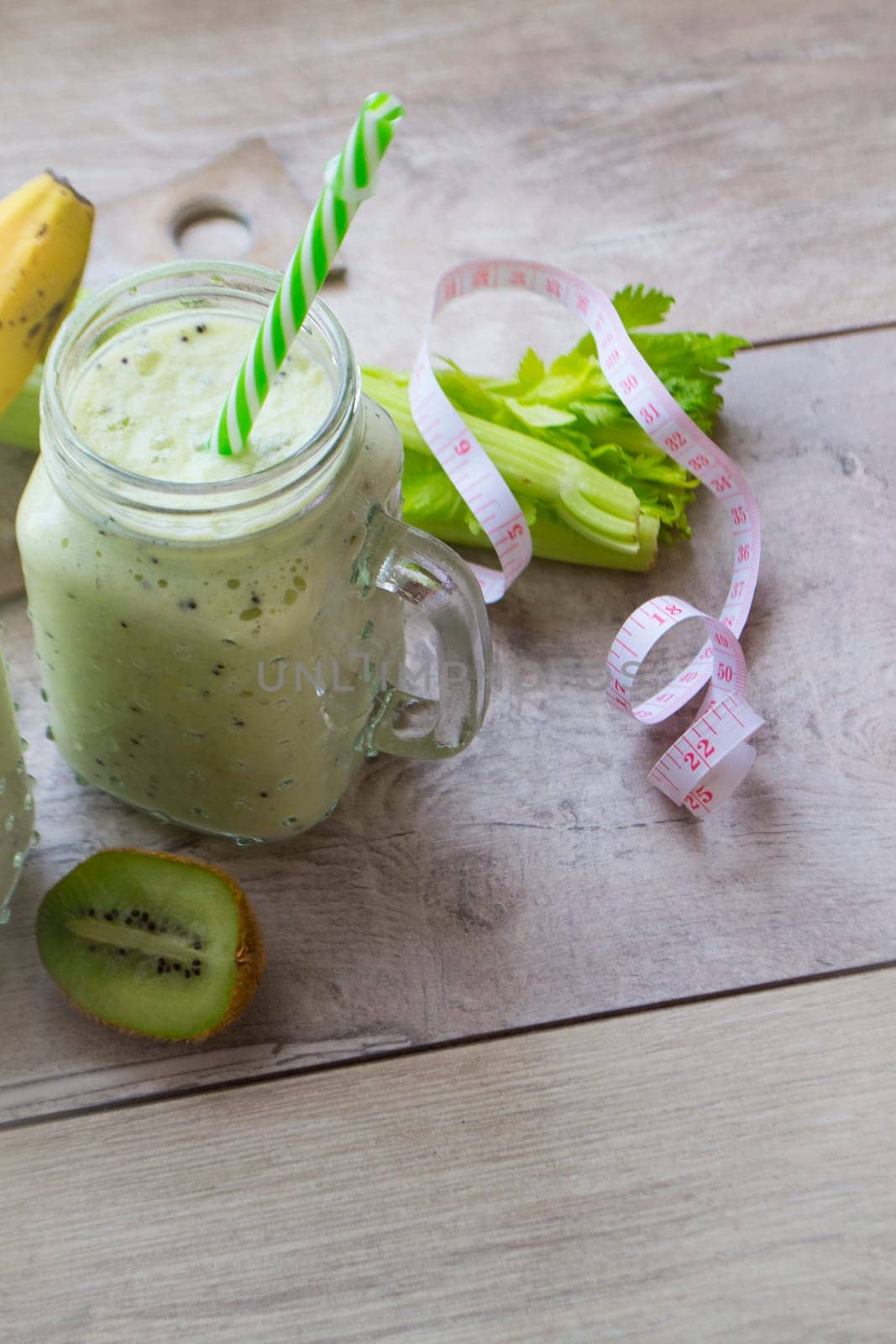 Celery healthy green smoothie in jar on grey background, vertical image