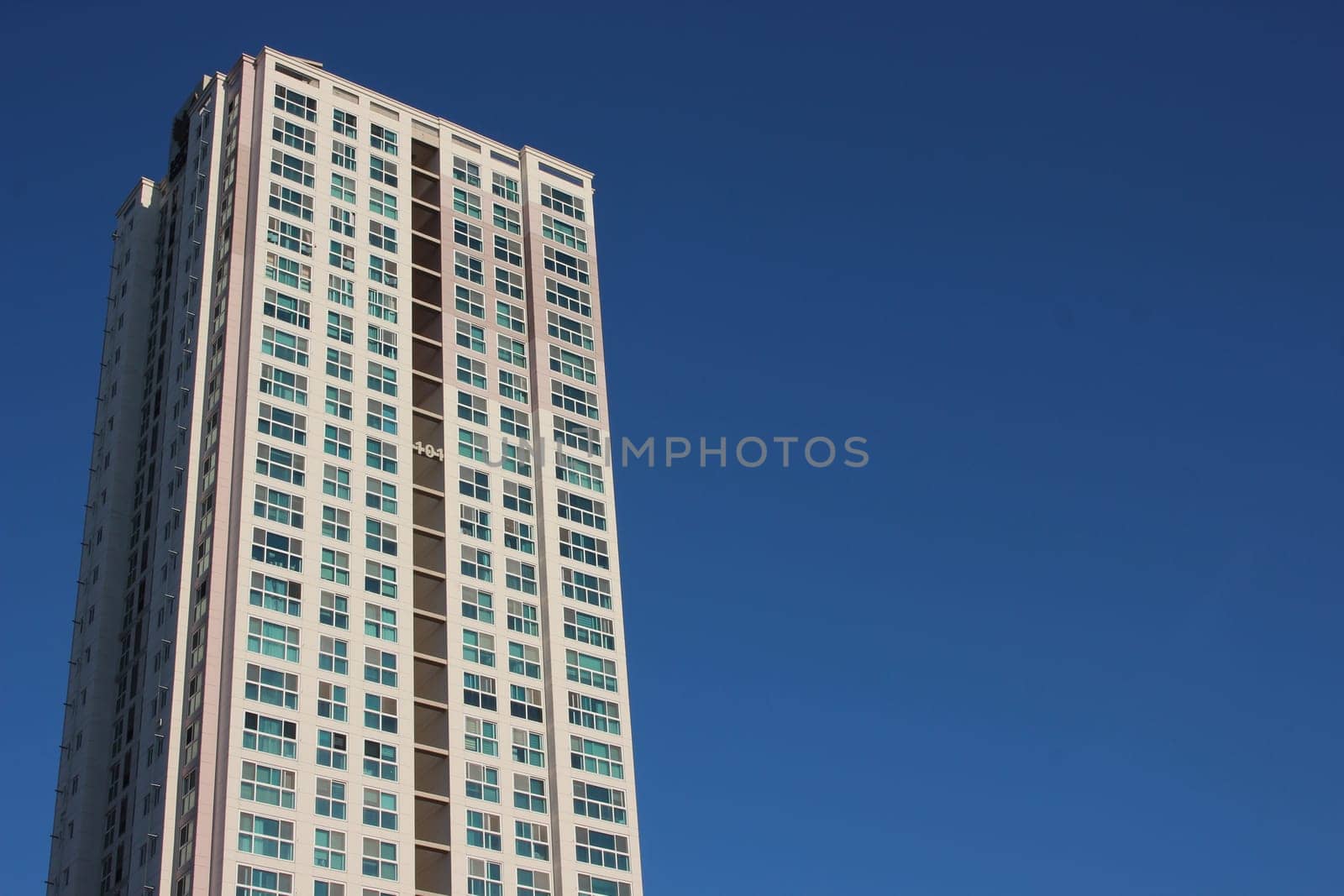 The wide-angle view of a skyscraper commercial building with blue sky on sunny day.