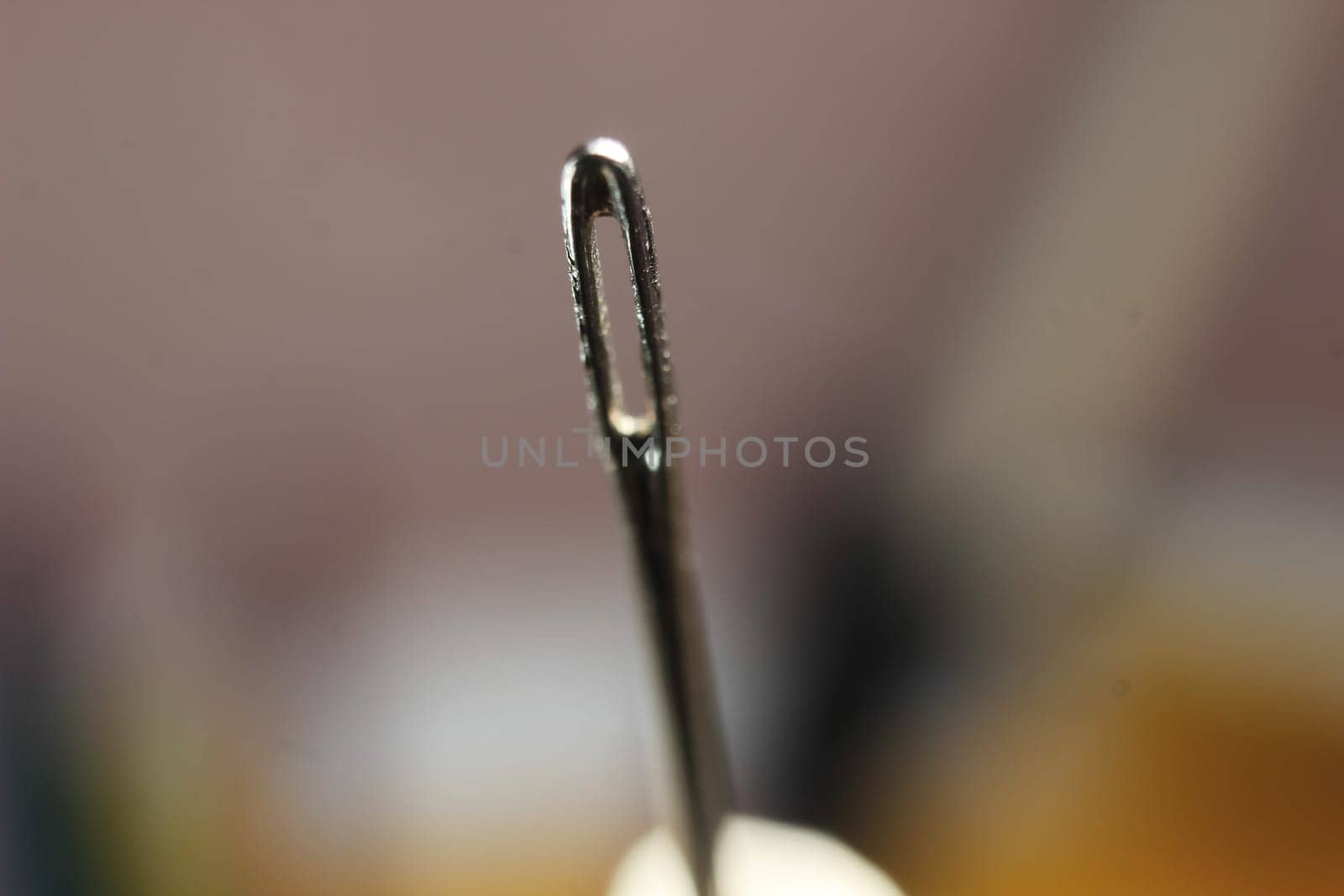 Macro photograph of sewing needle. Small needle with empty eyelet, isolated over the black background.