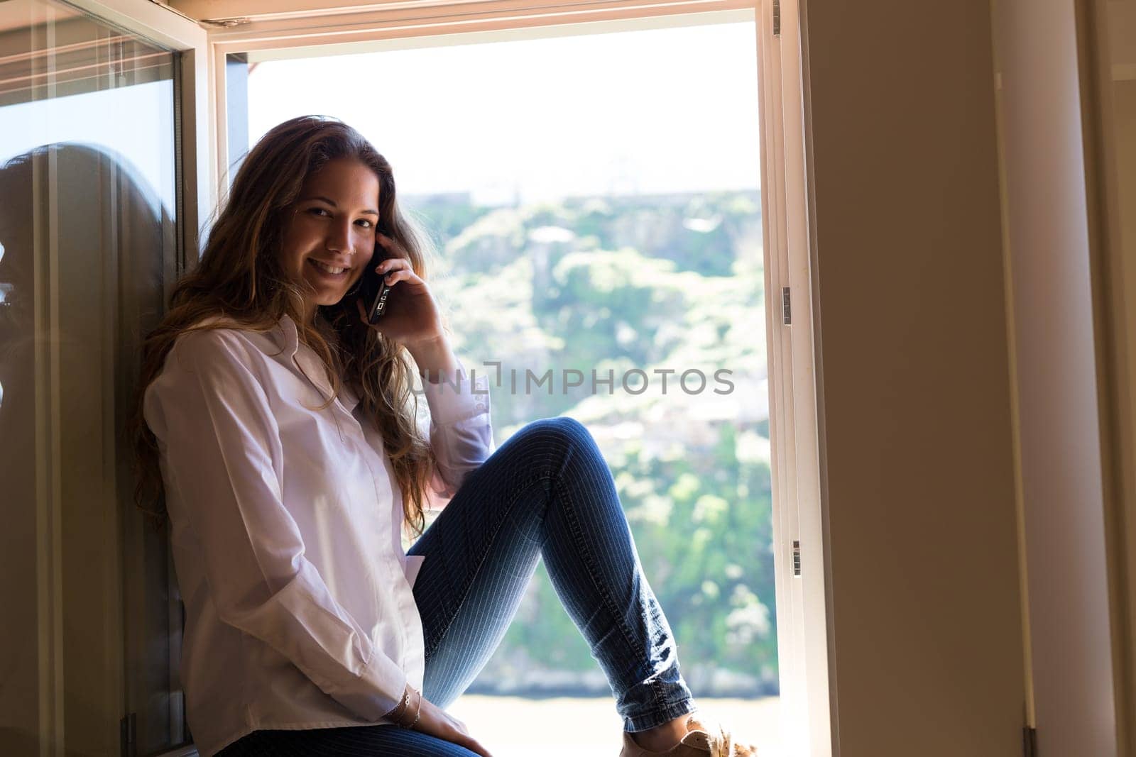 Young woman catching some sun at the balcony while using her new smartphone