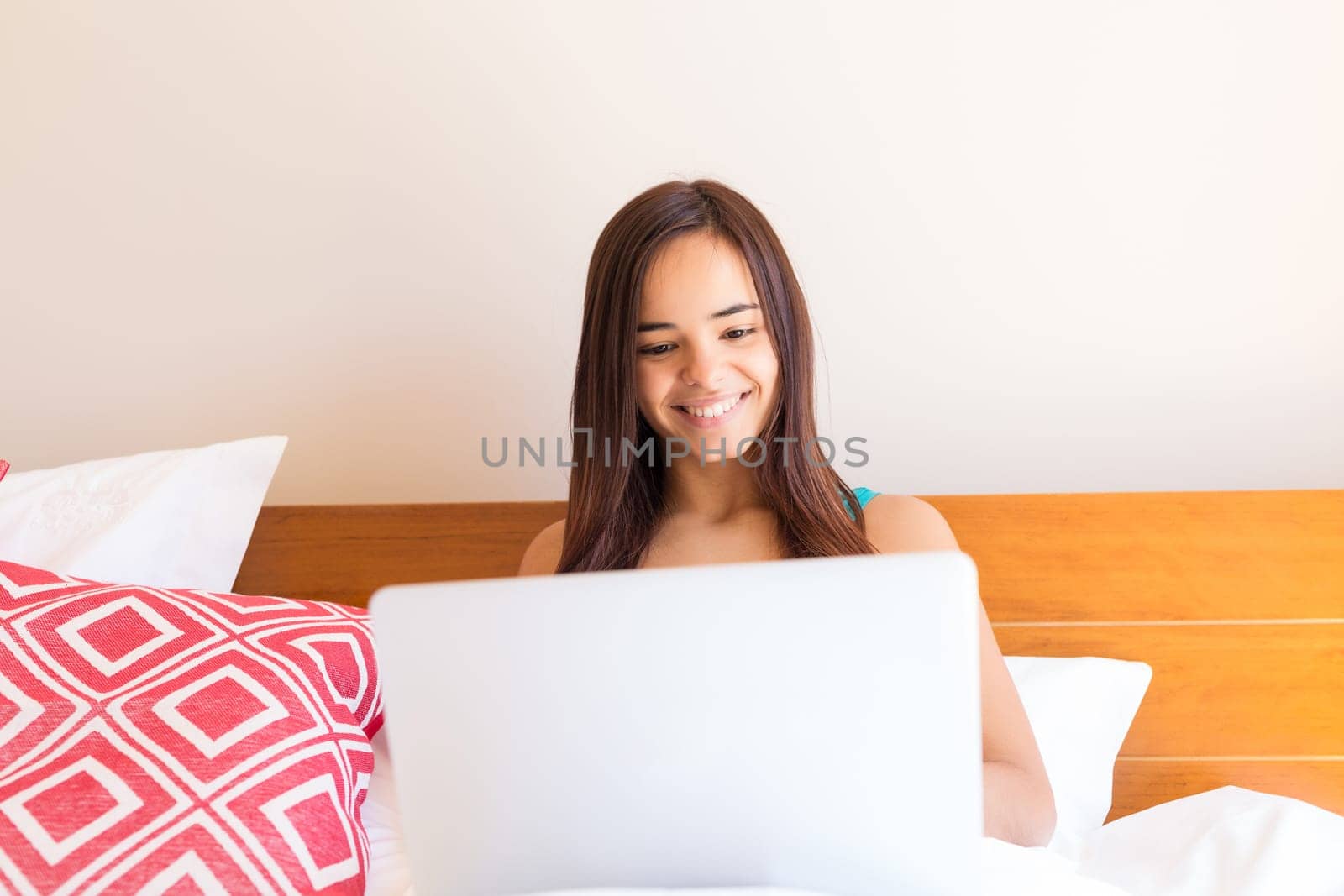Young woman relaxing with her computer in bed