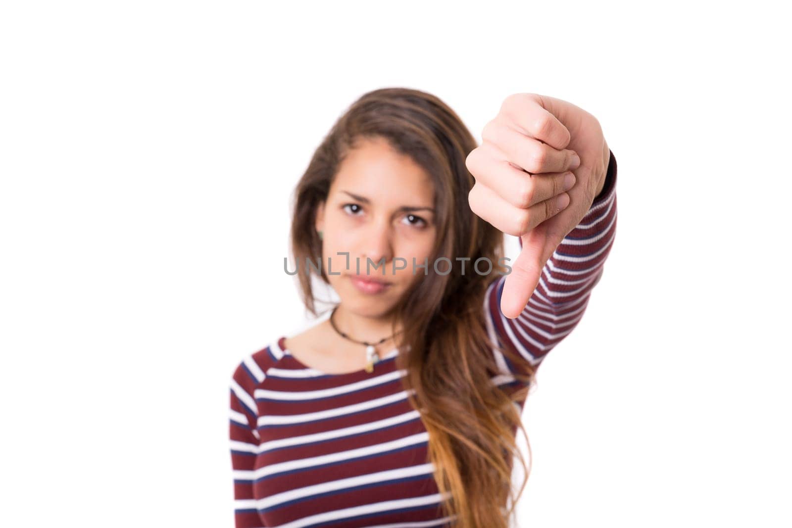 Studio shot of a young woman signaling thumbs down