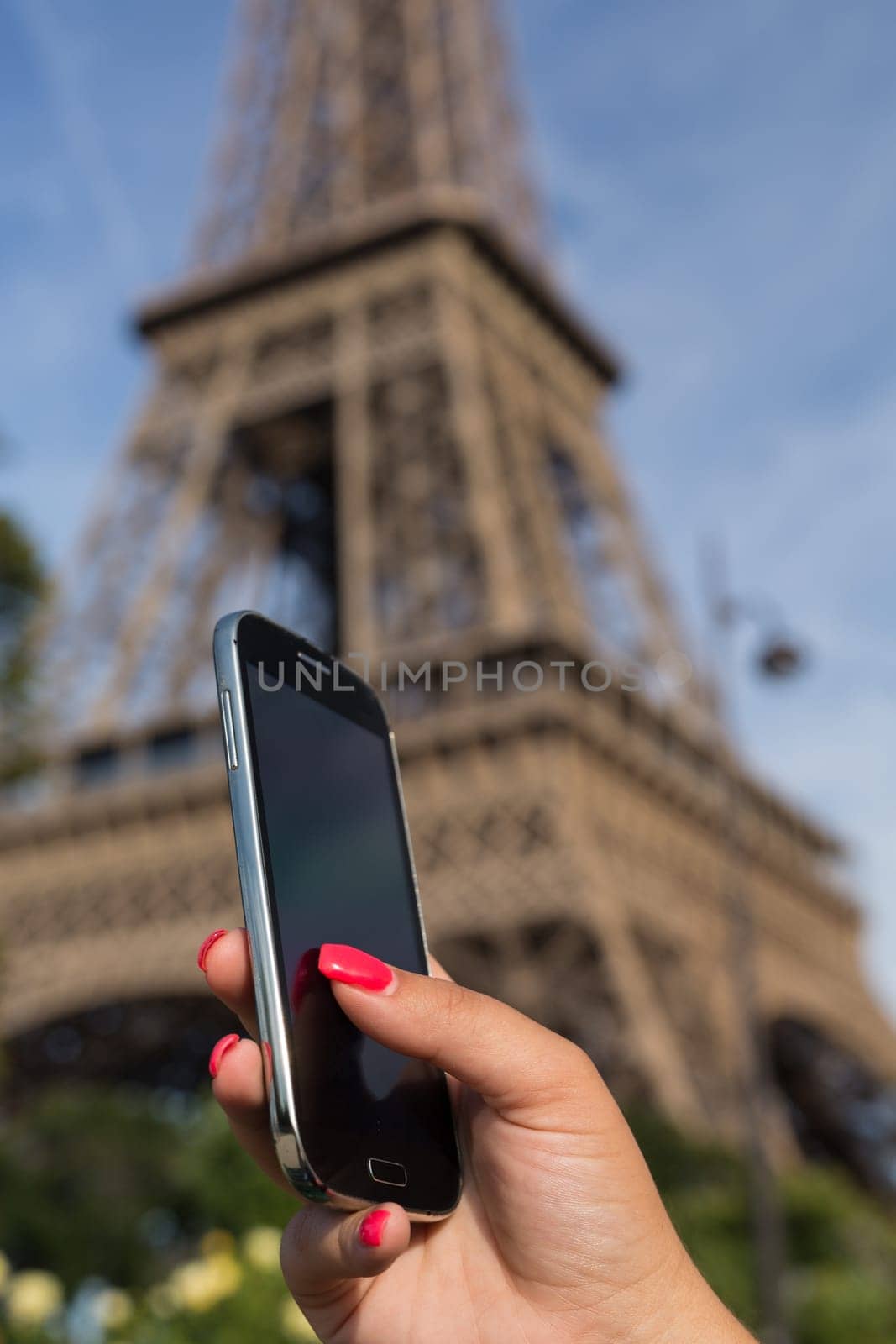 Woman consulting her smartphone with Eiffel Tower on background