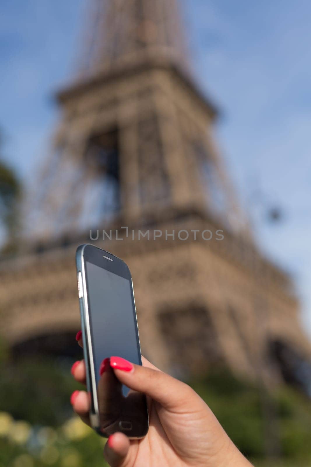 Woman consulting her smartphone with Eiffel Tower on background