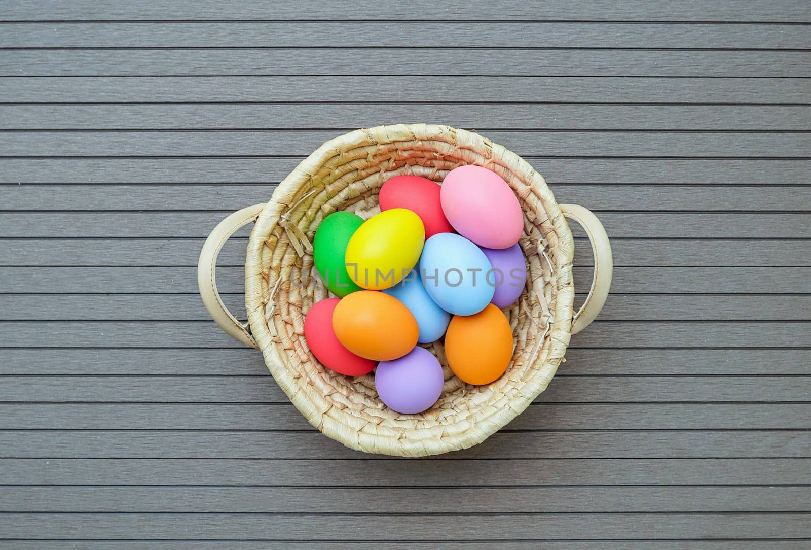Colorful easter eggs in the basket on wood background with space