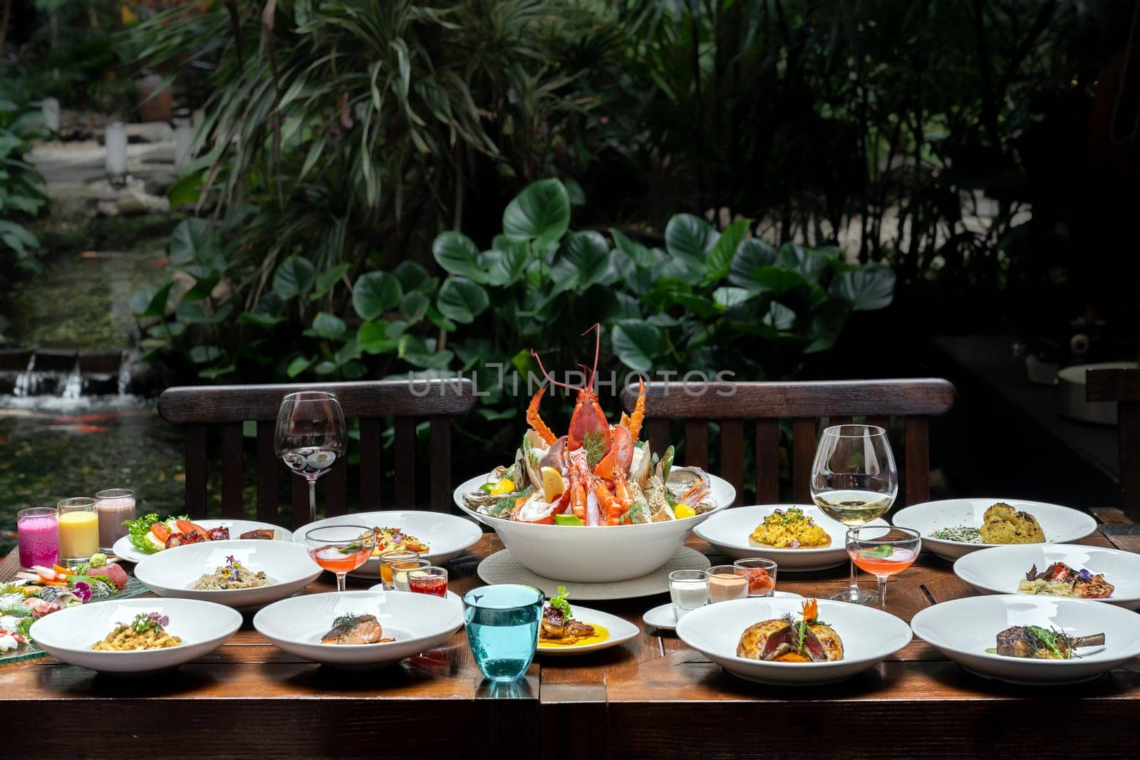 Side view premium variety of international food in garden of restaurant of lobster shrimp steak beef lamb pasta spaghetti risotto rice sushi sashimi and wine using for buffet food drink background.