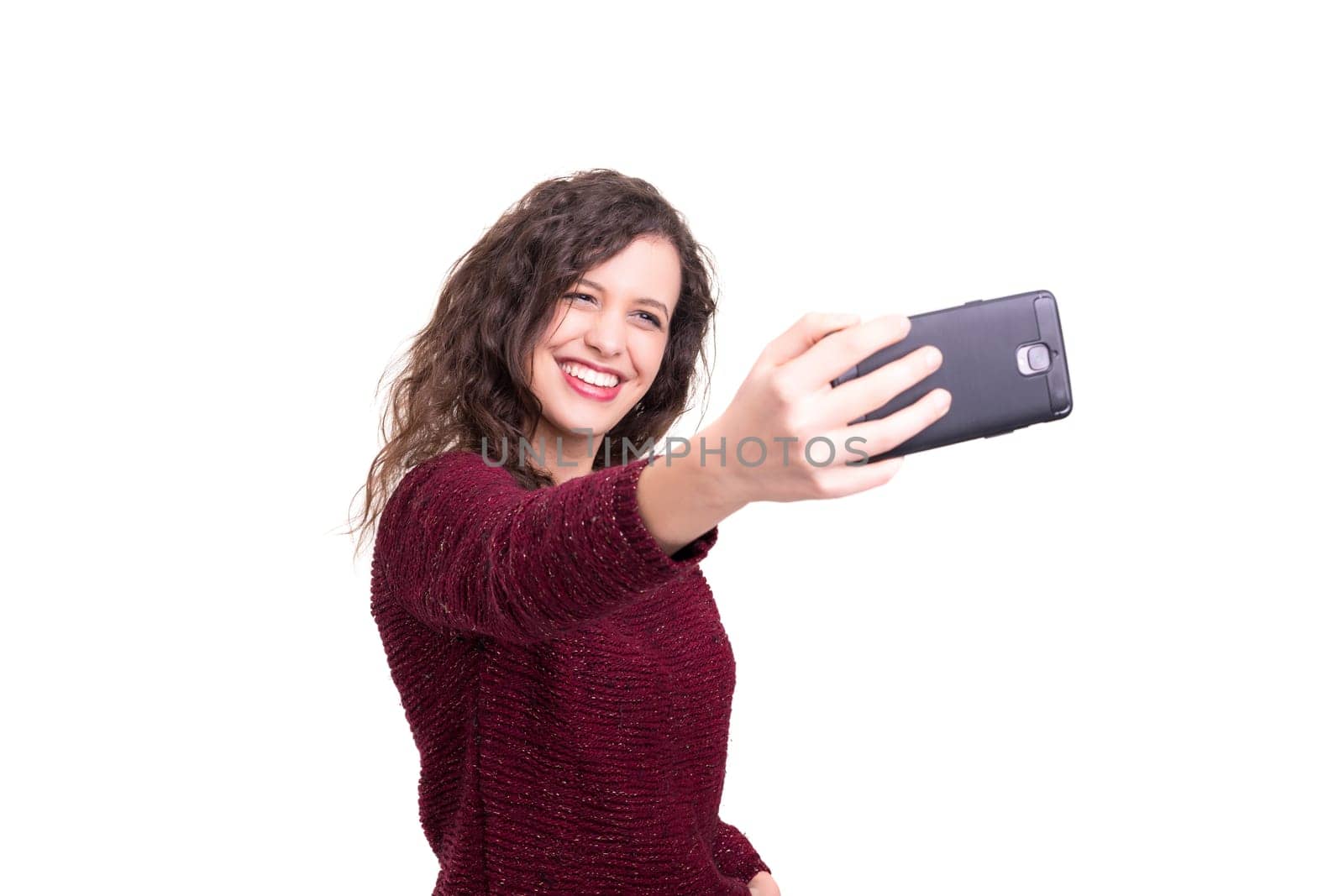 Happy young woman taking self portrait photography through smart phone over white background.