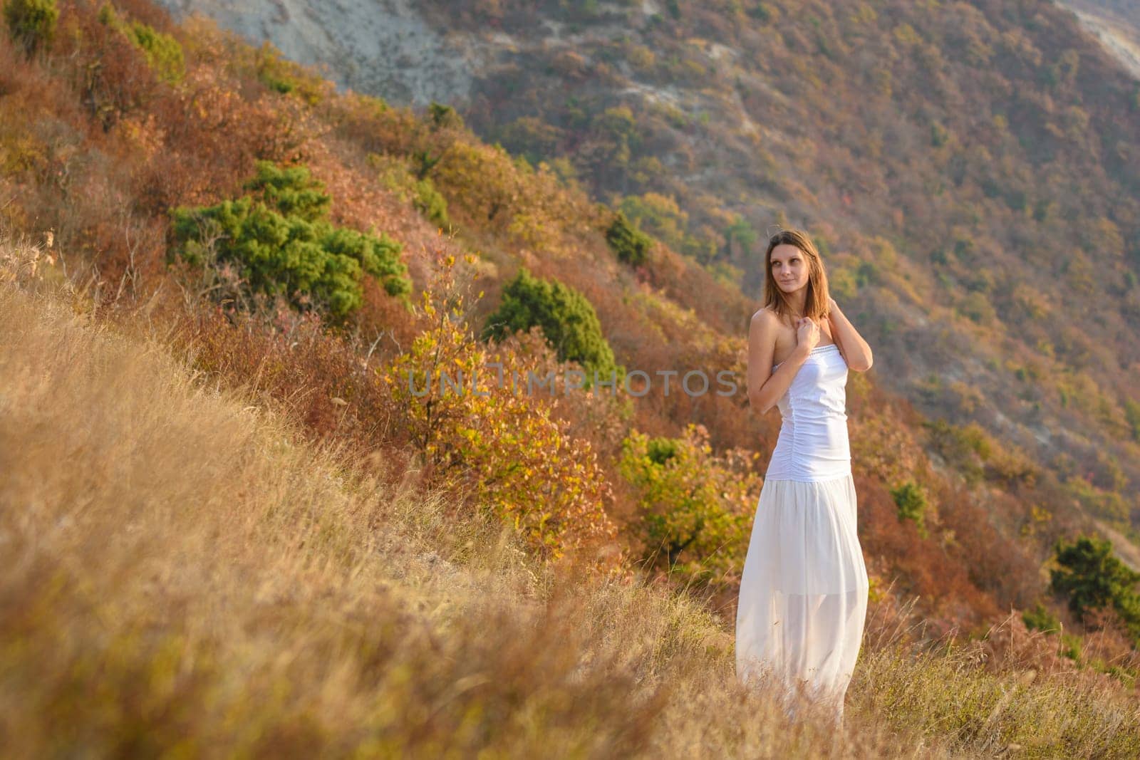 Beautiful slender girl in white clothes on the background of a beautiful mountain landscape