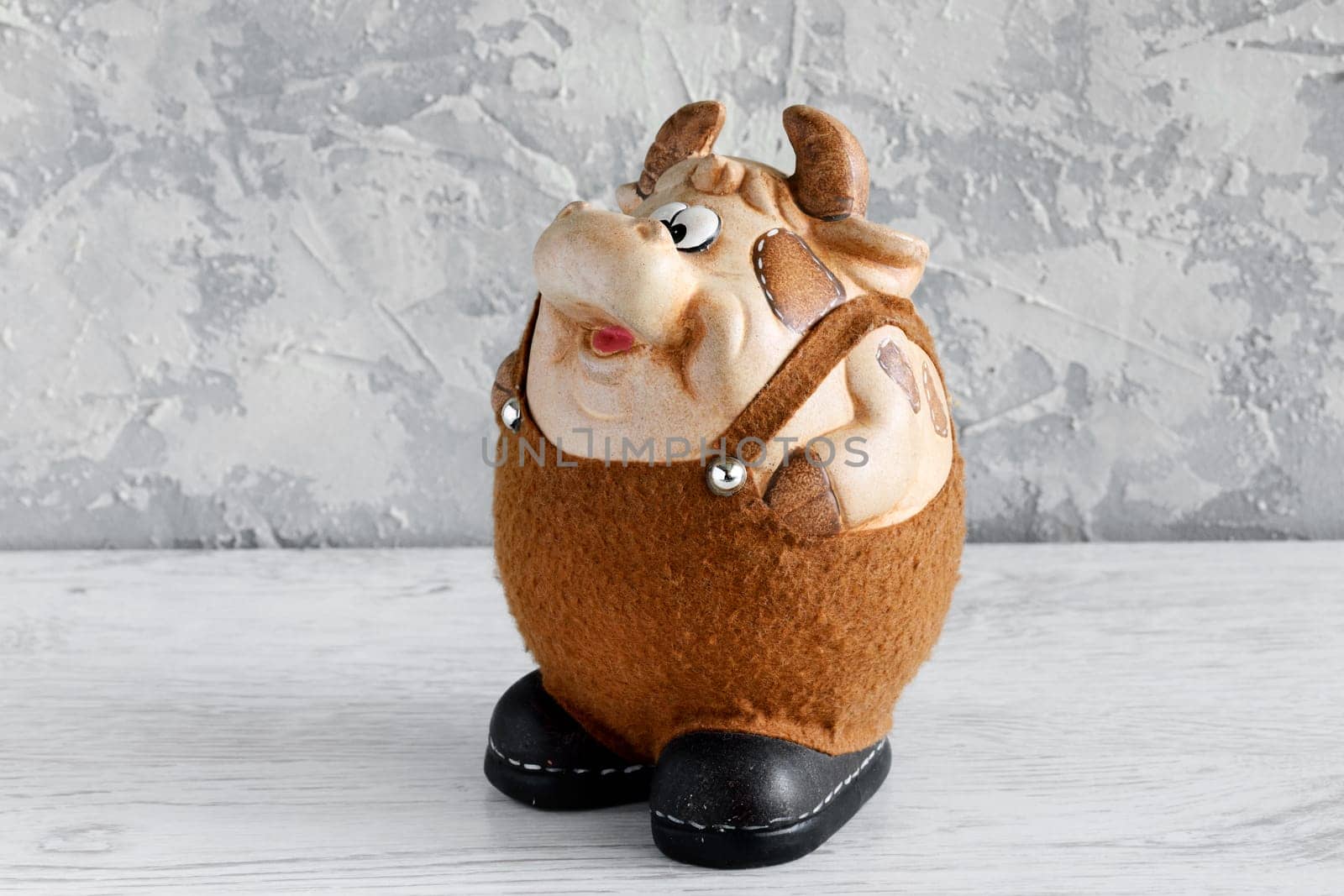 Clay bull figurine in black and white decorated with Christmas decorations on a white background. New year of the bull