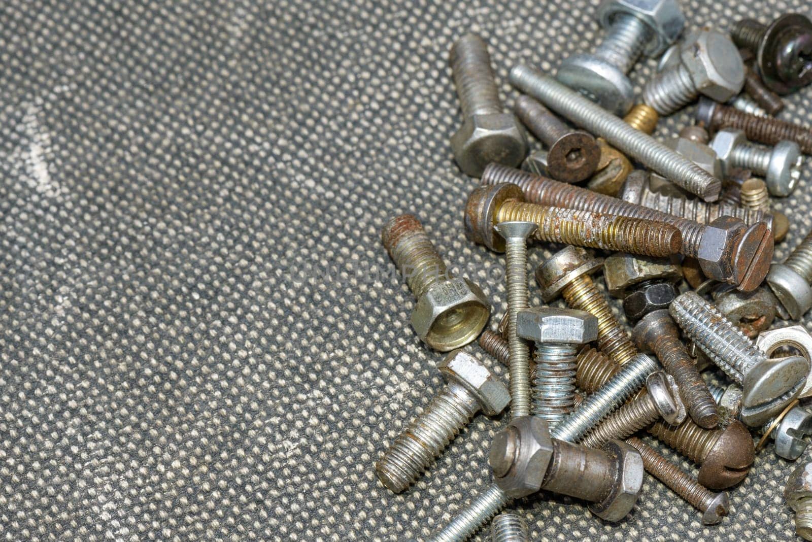 Several old screws on a grey texile background