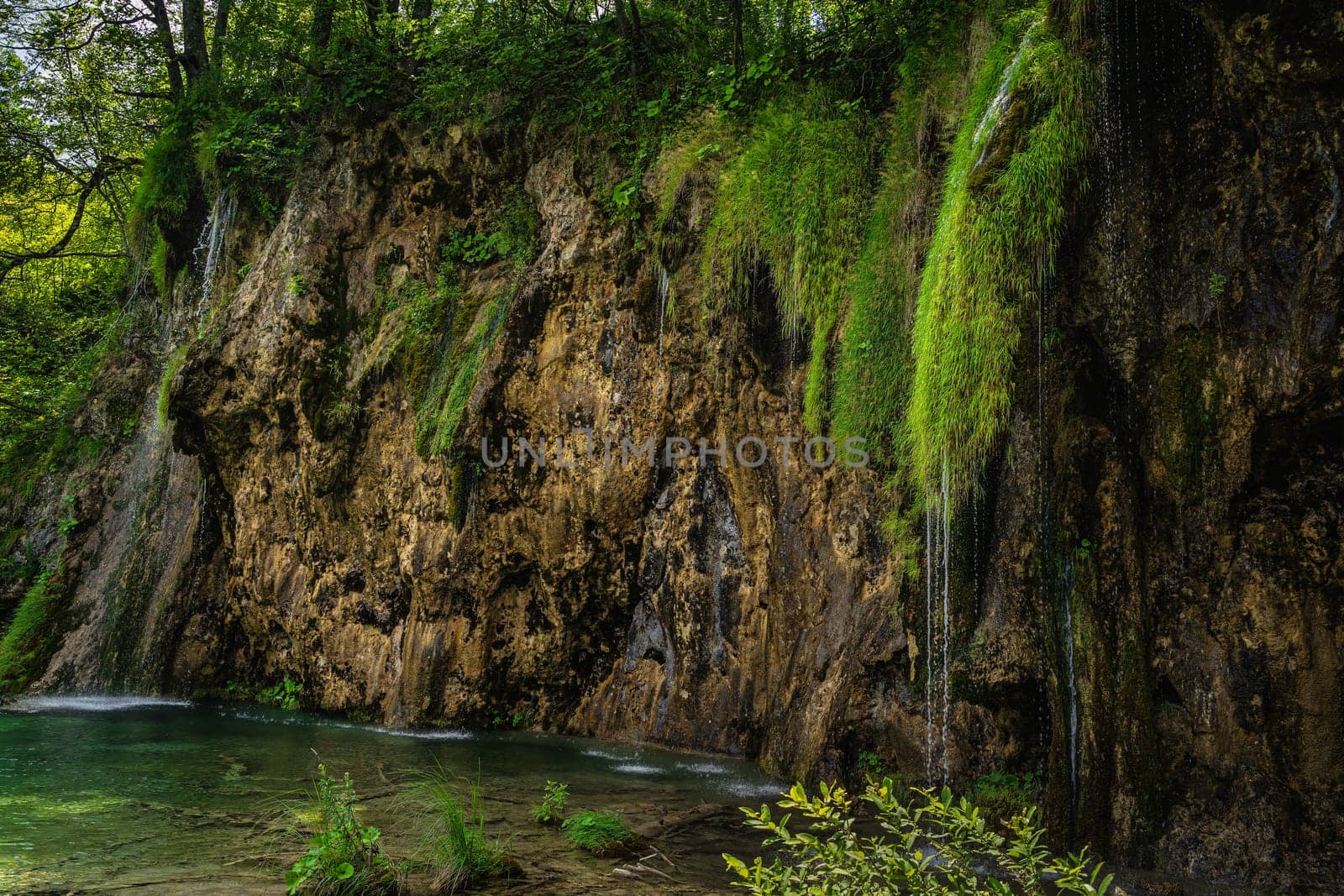 Streaks of water coming down from lichens hooked at tall cliff or waterfall in Plitvice Lakes National Park UNESCO World Heritage, Croatia
