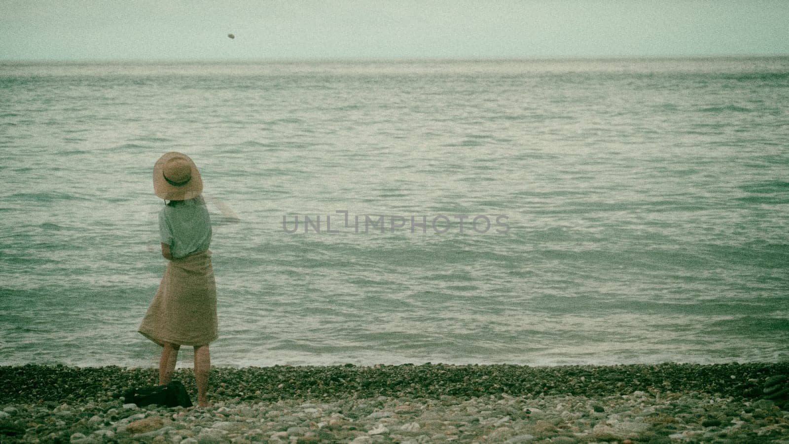 The Girl throwing stones at the beach