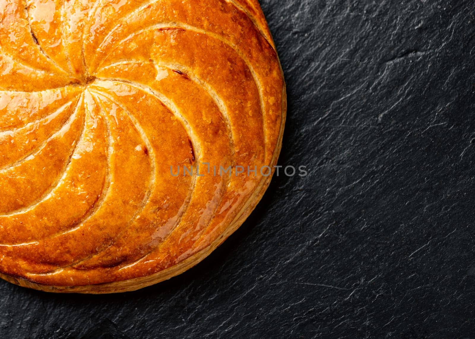Epiphany cake or galette des rois in French on black slate background