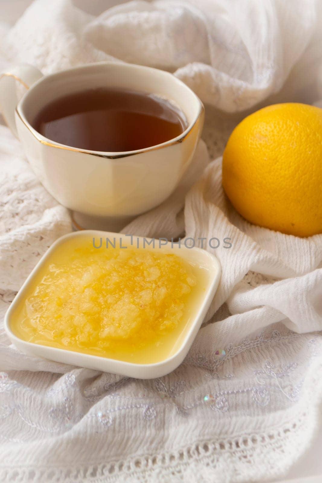Healthy bowl of pure honey with honey dipper and lemon fruit and puree on vintage white background. Vertical image