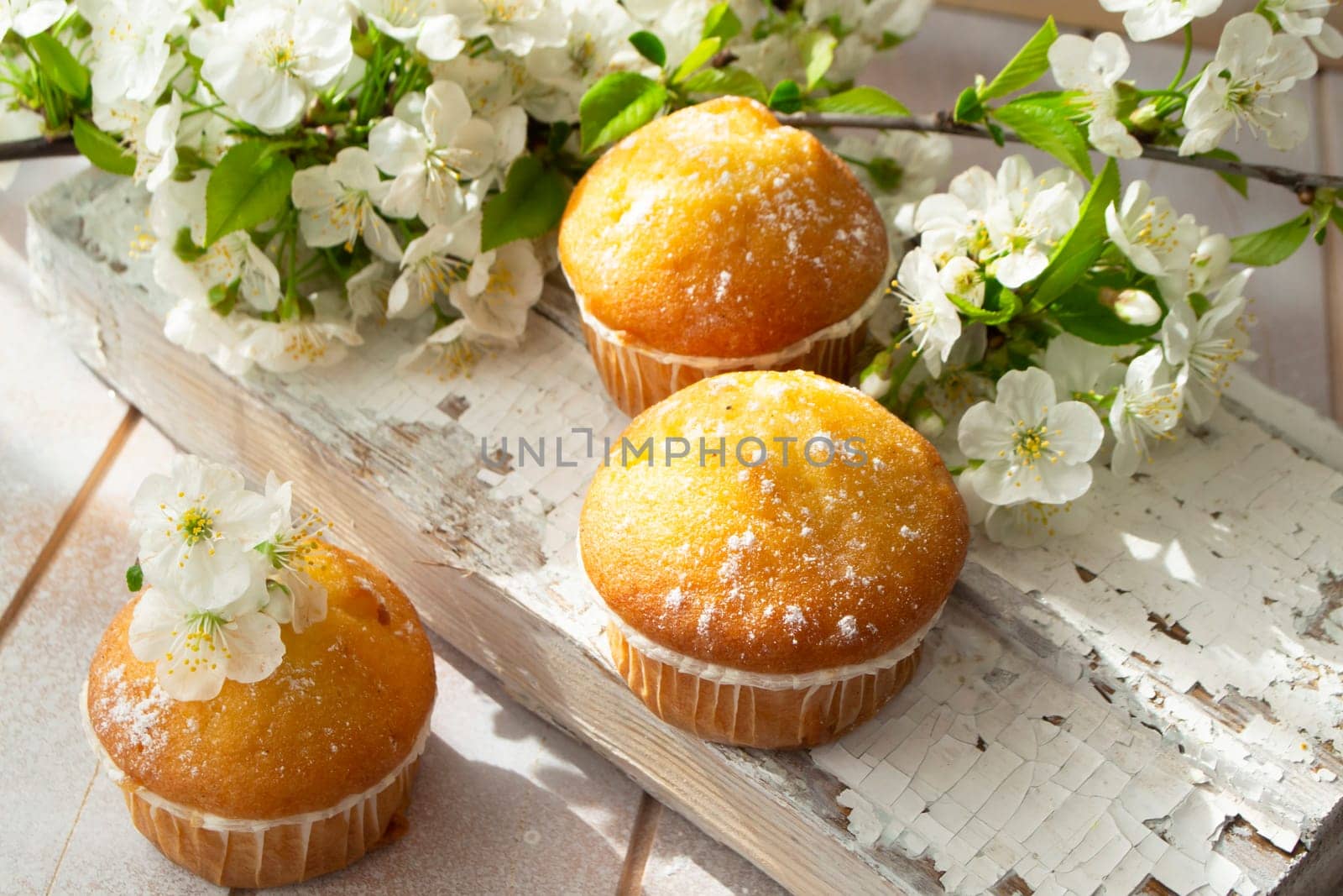 freshly baked homemade muffins, decorated with petals of spring flowers on a shabby wooden table