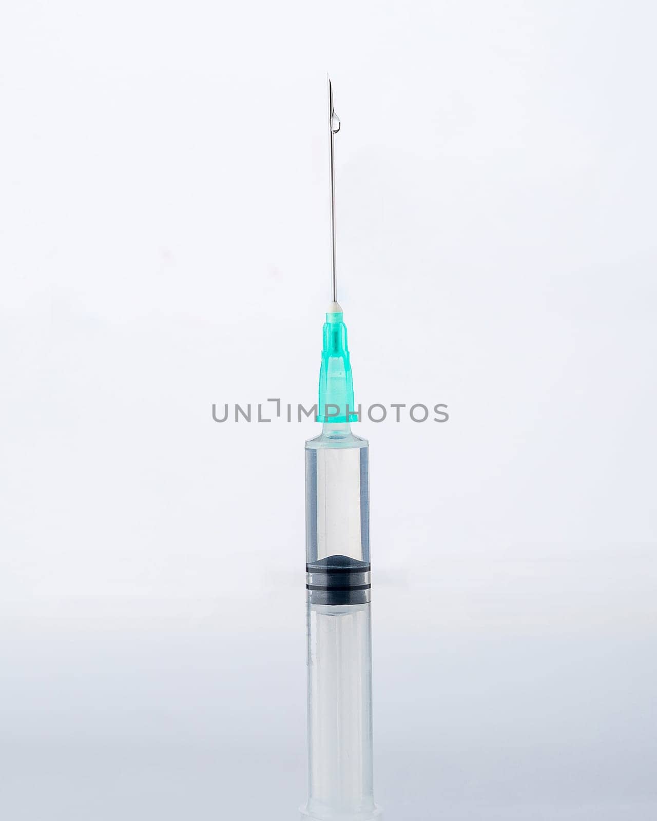 Close-up of a syringe and a drop of liquid on it, on a white background. Covid-19 vaccine concept.
