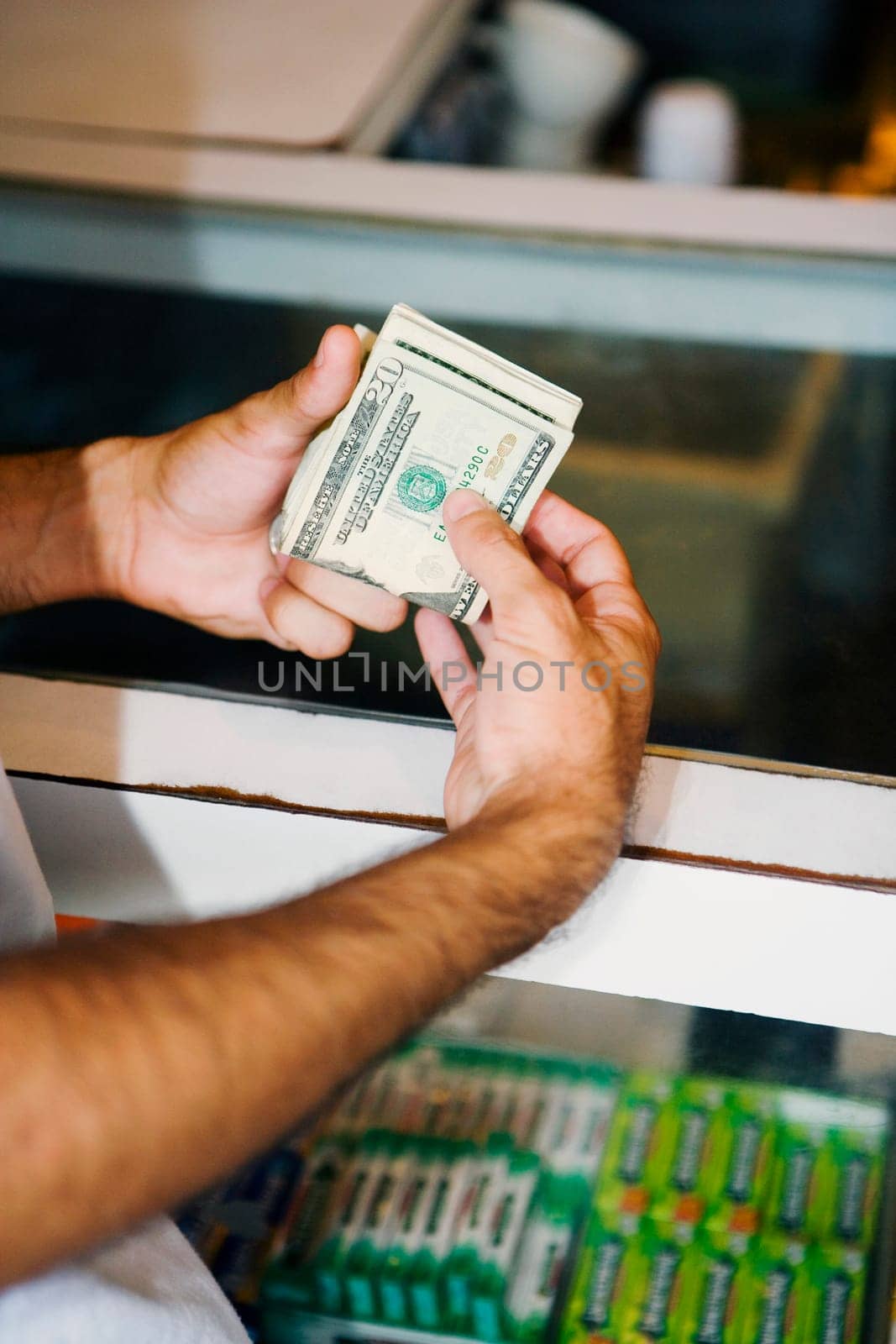 Close-up of a man's hand holding a wad of twenty dollar banknotes
