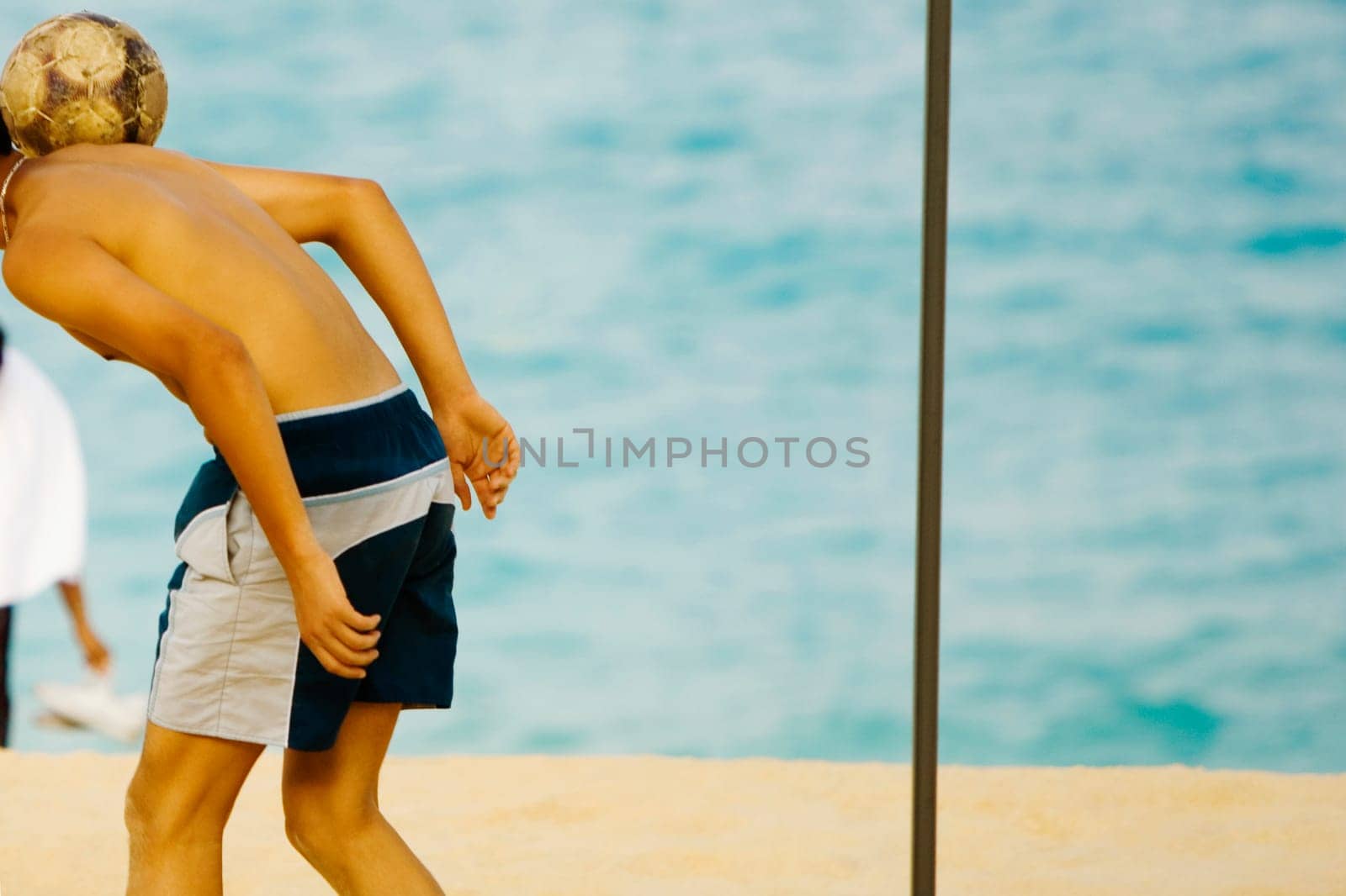 Side profile of a teenage boy playing soccer on the beach