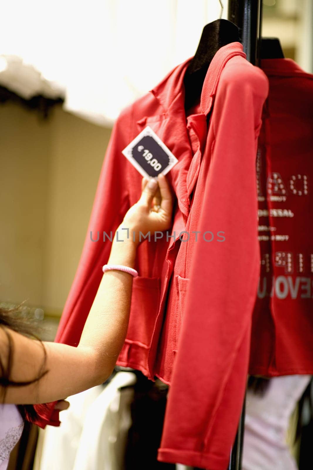 Close-up of woman's hand checking the price tag of a coat in a clothing store