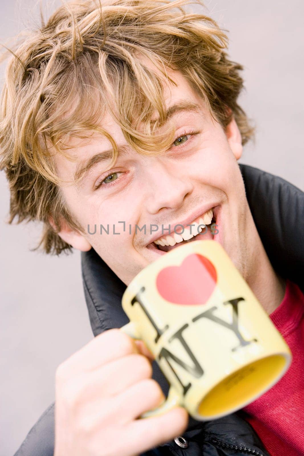 Portrait of a young man holding a coffee cup and smiling