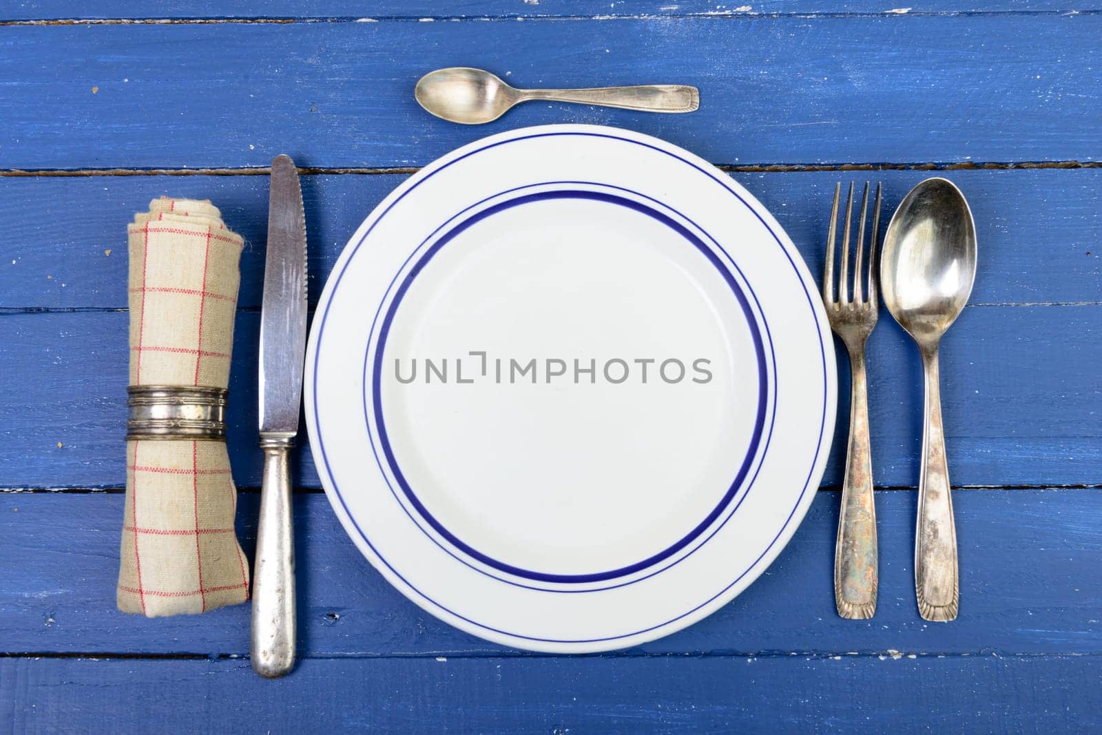 plate with silver cutlery on an old blue table