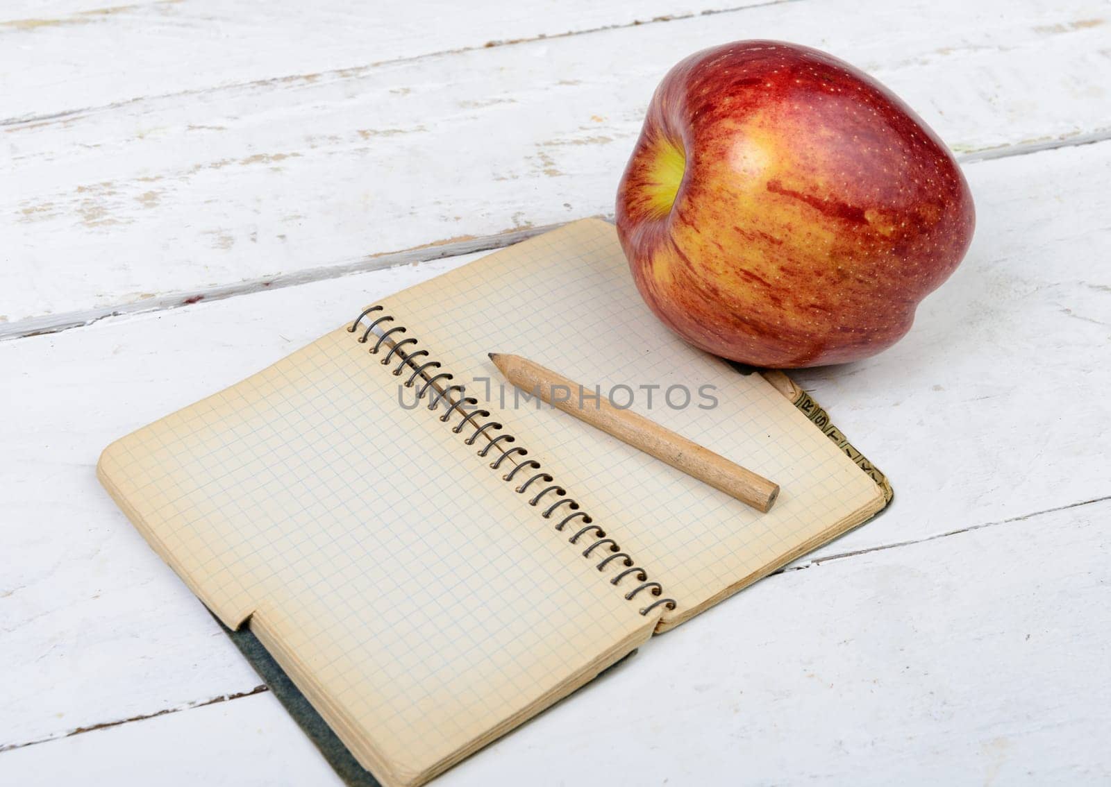 Apple and notebook on a table with pencil