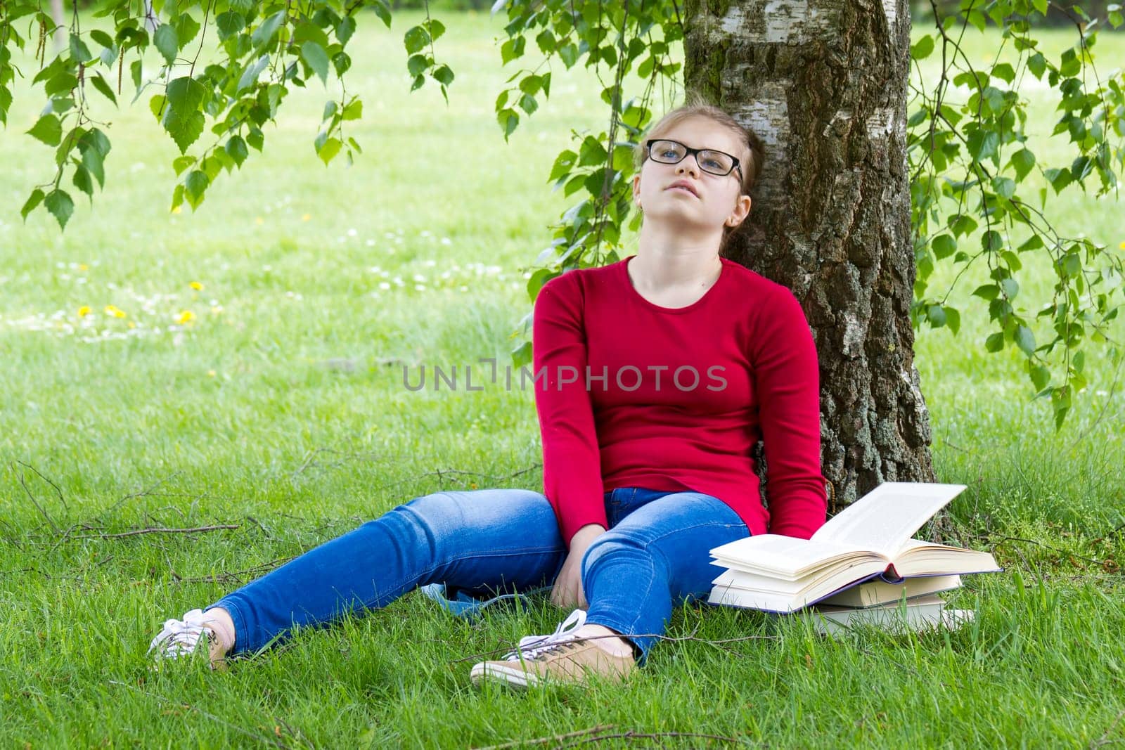 Young girl reading book in park in spring day
